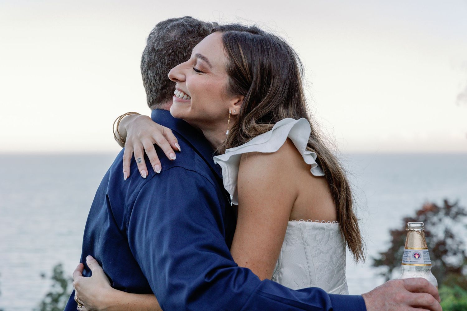 Emotional hugs and embraces shared during an outdoor waterfront celebration.