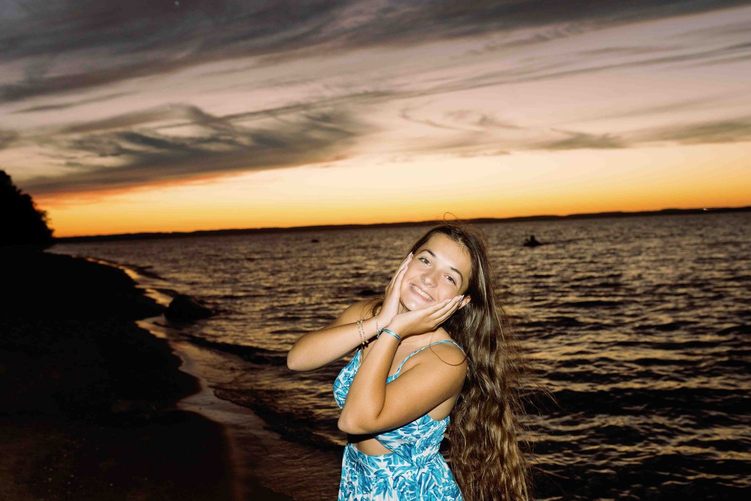 Sunset beach photoshoot with blue dress against golden sky and ocean backdrop.