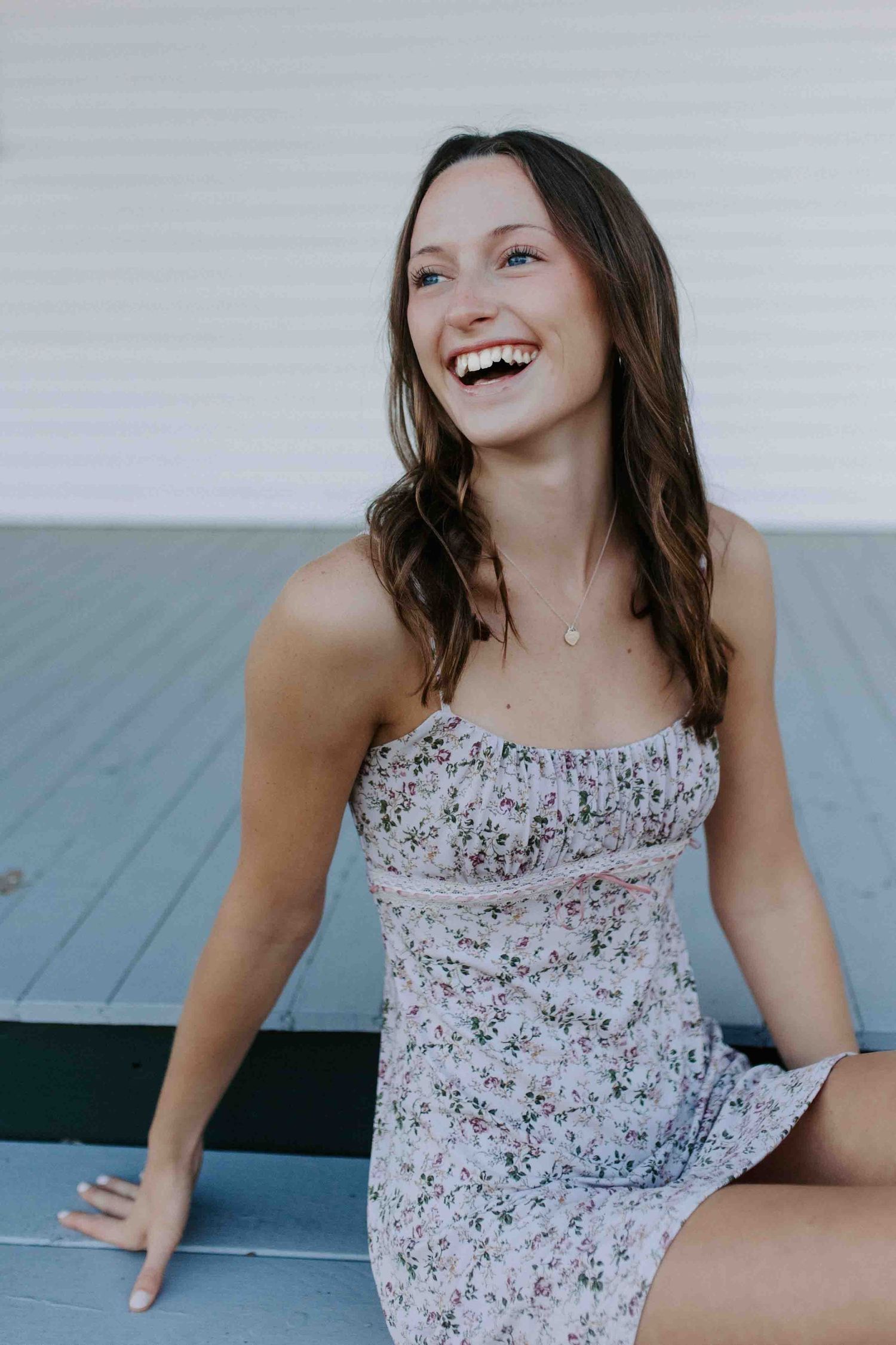 Candid portrait session on a blue porch showing joyful expressions and a floral sundress.