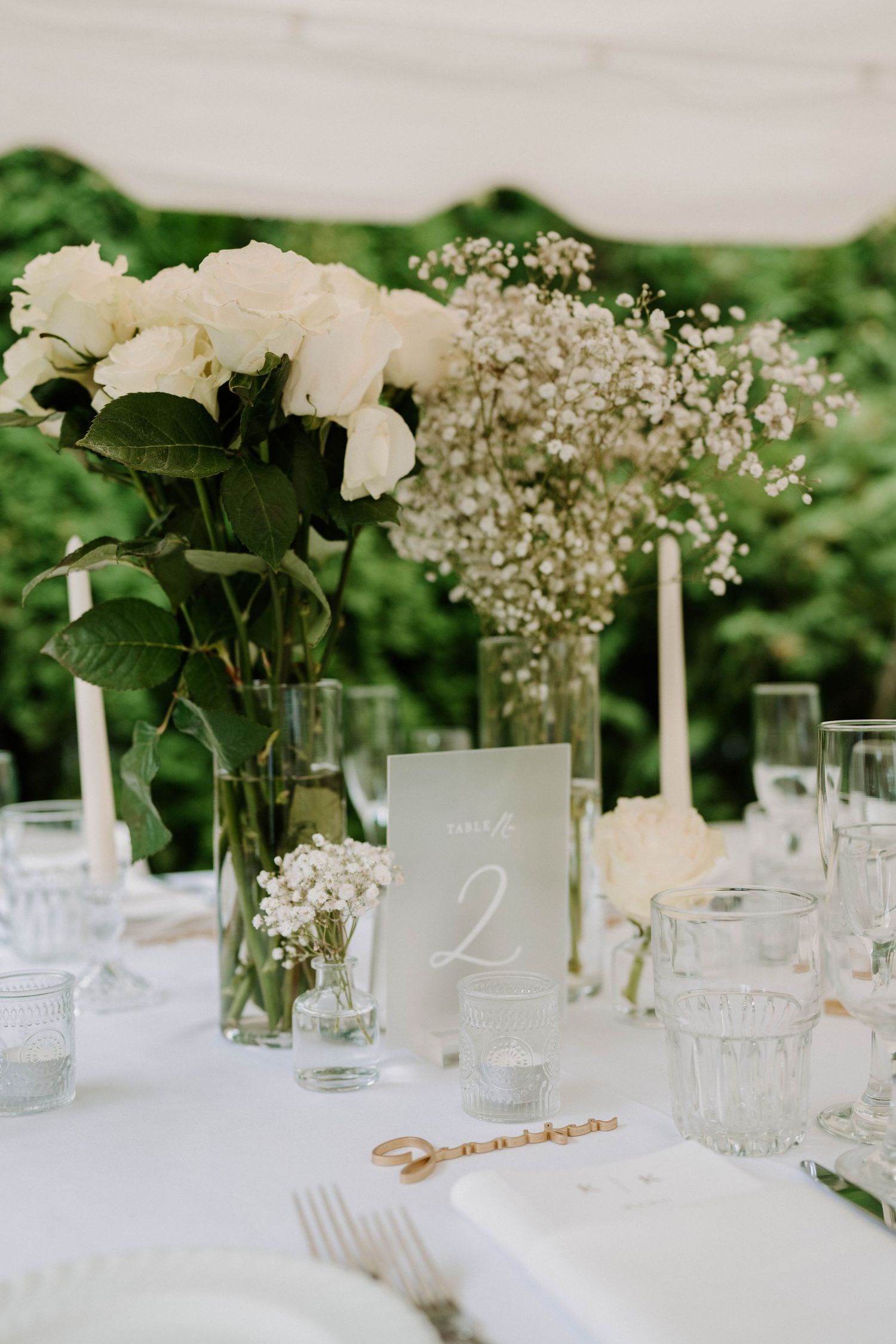 Wedding table settings with white linens, floral centerpieces, and table numbers.