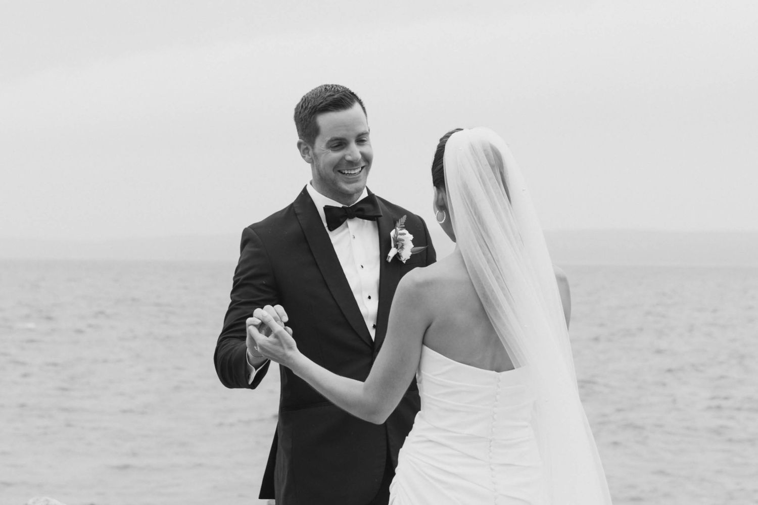 A couple shares their first look moment during a seaside wedding ceremony.