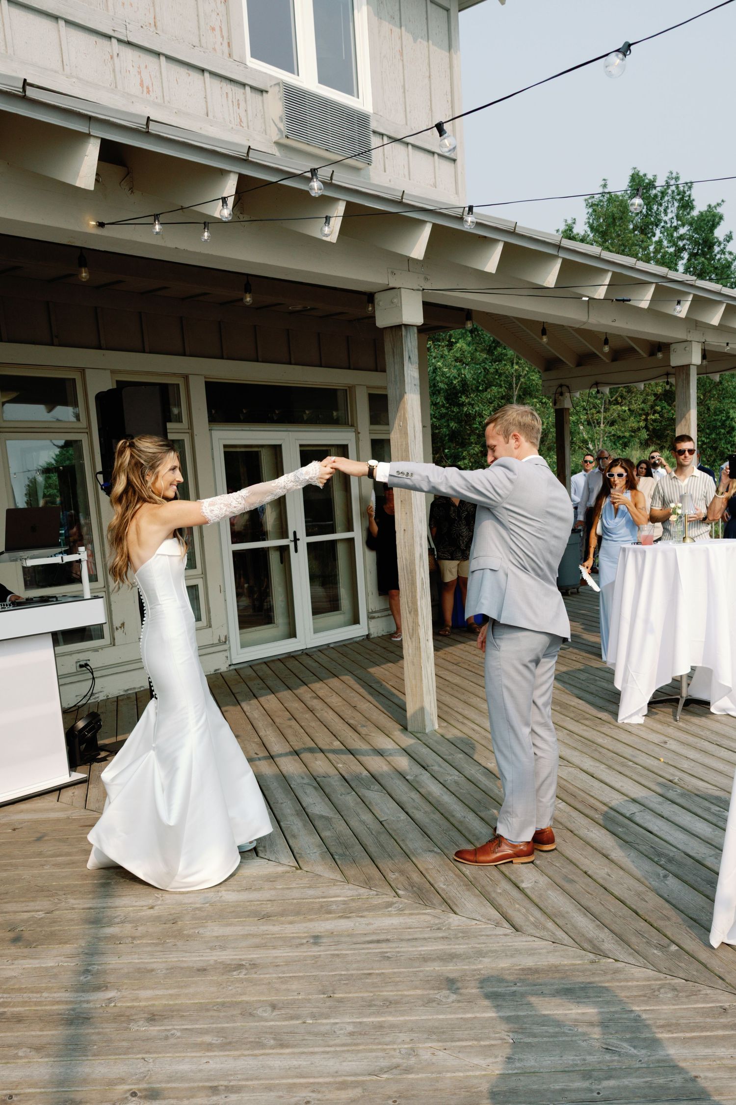 Couple dancing on an outdoor wooden deck during their wedding celebration.