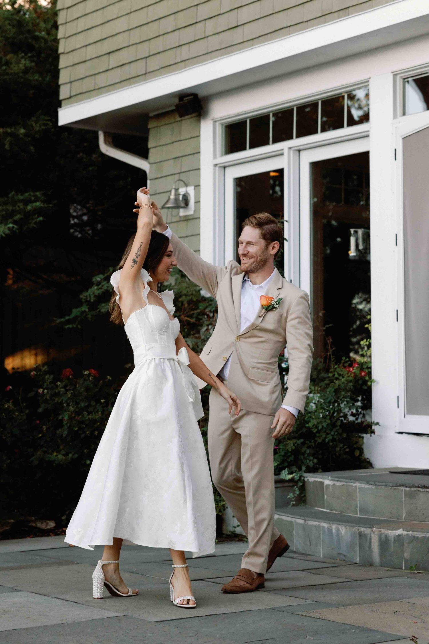 A couple performs a playful dance sequence on a porch in formal attire.