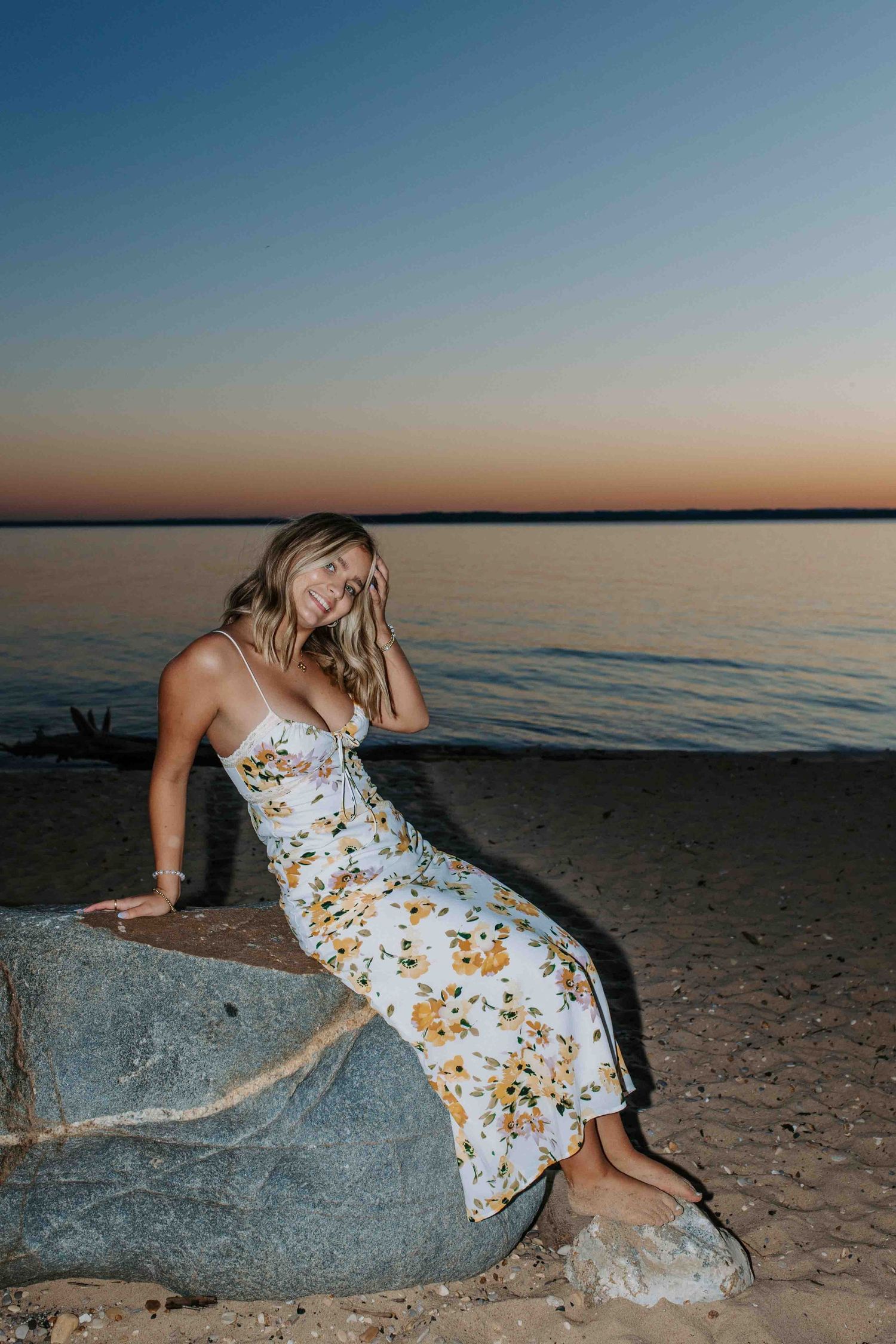 Summer photoshoot on beach with floral dress and natural rock formations.