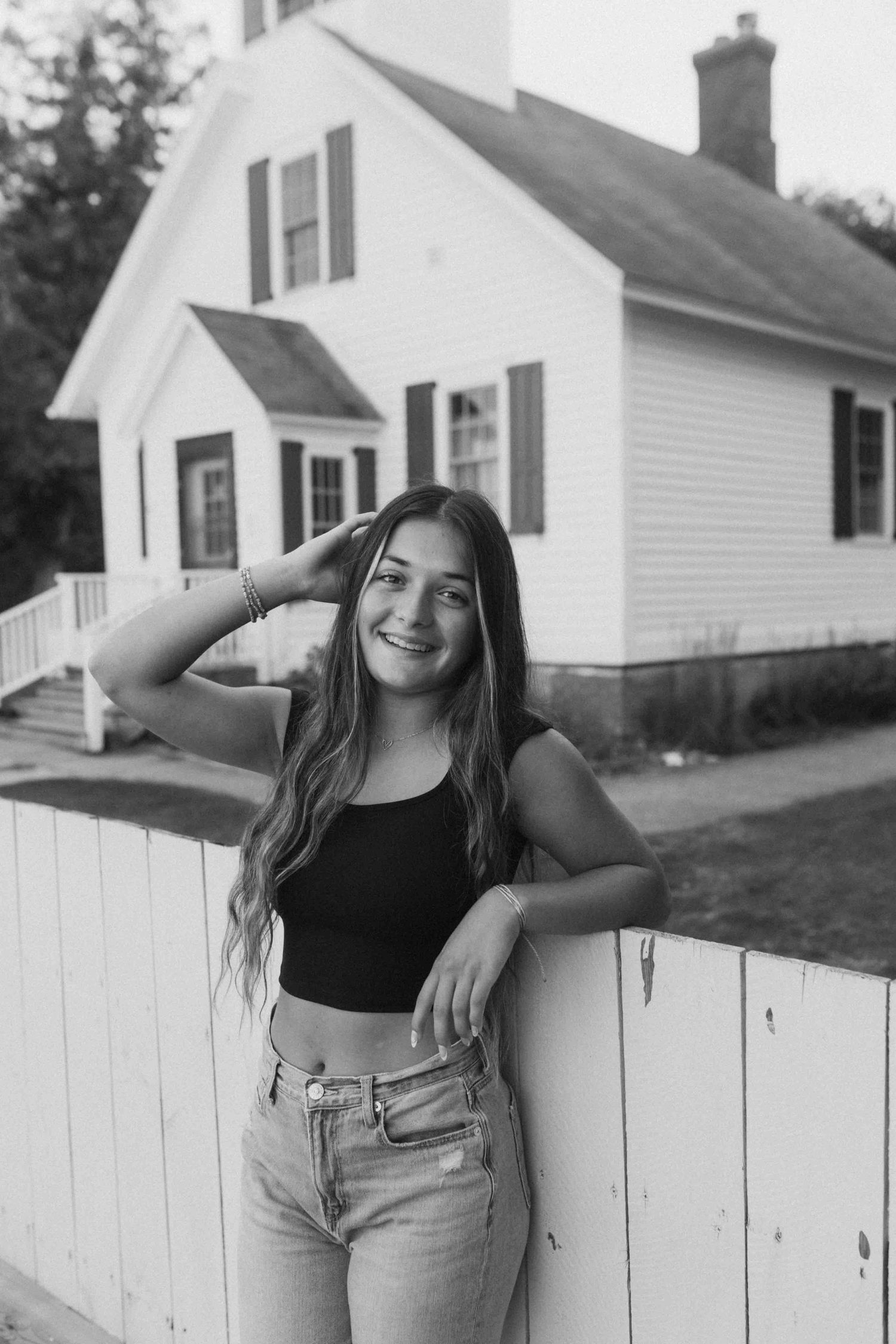 Black and white portraits against rustic white fence and farmhouse backdrop.