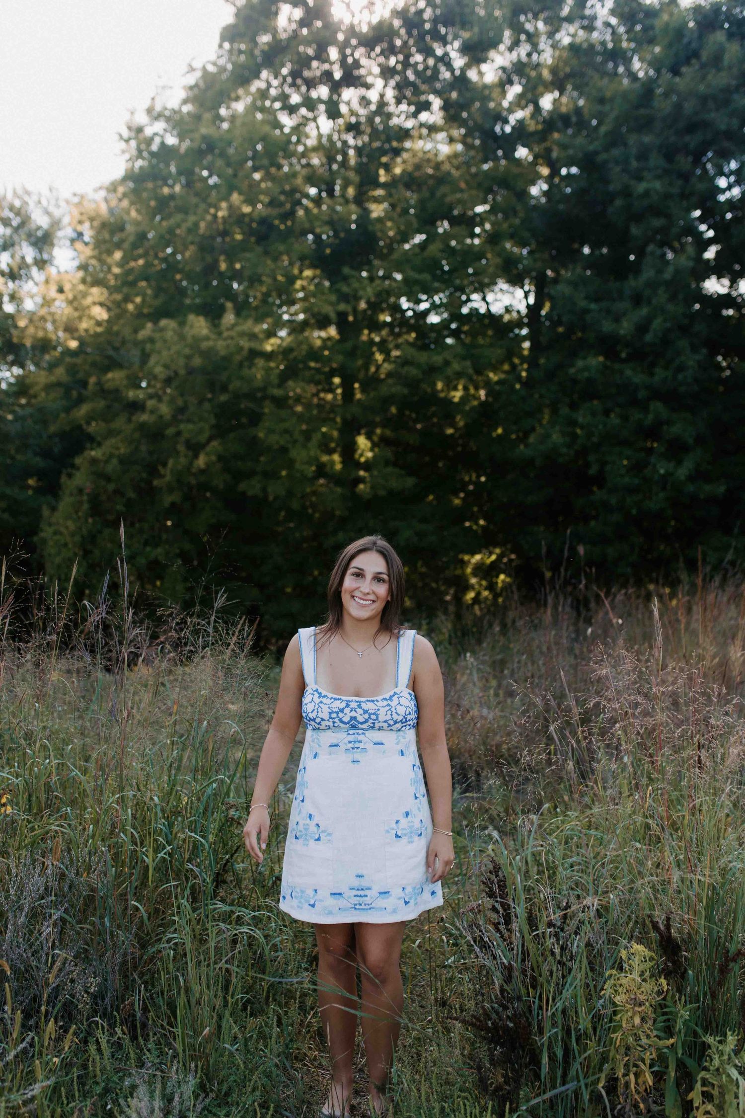 Casual outdoor fashion shoot featuring a white sundress with blue pattern details.