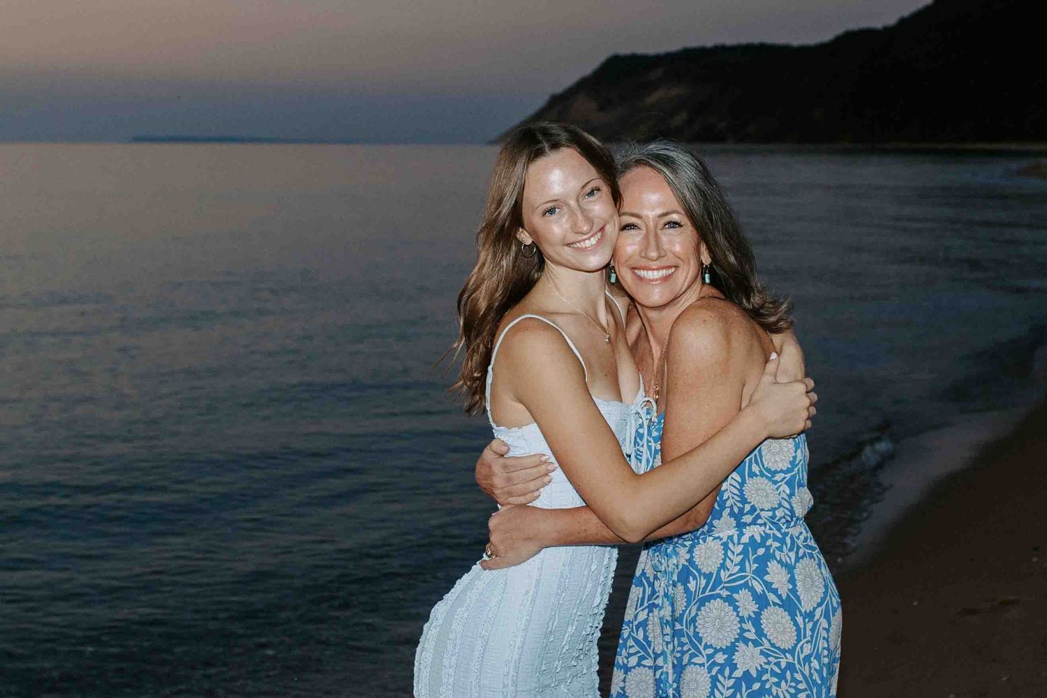 Friends sharing joyful embraces on the beach during golden hour.