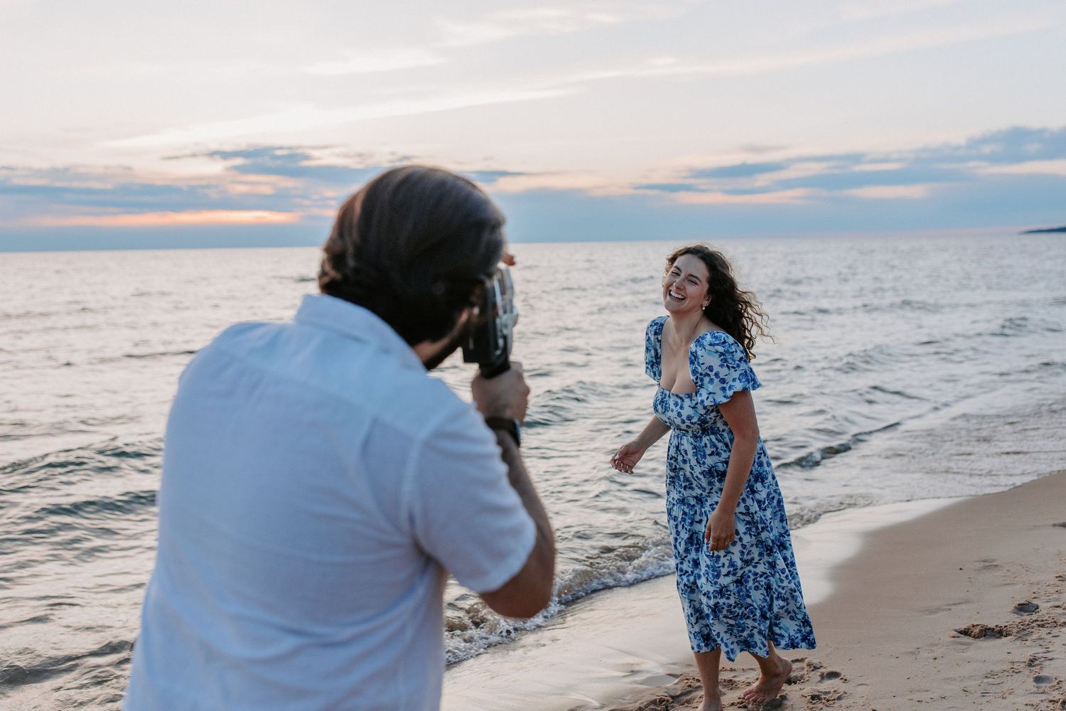Couple walking along shoreline during golden hour beach photoshoot.