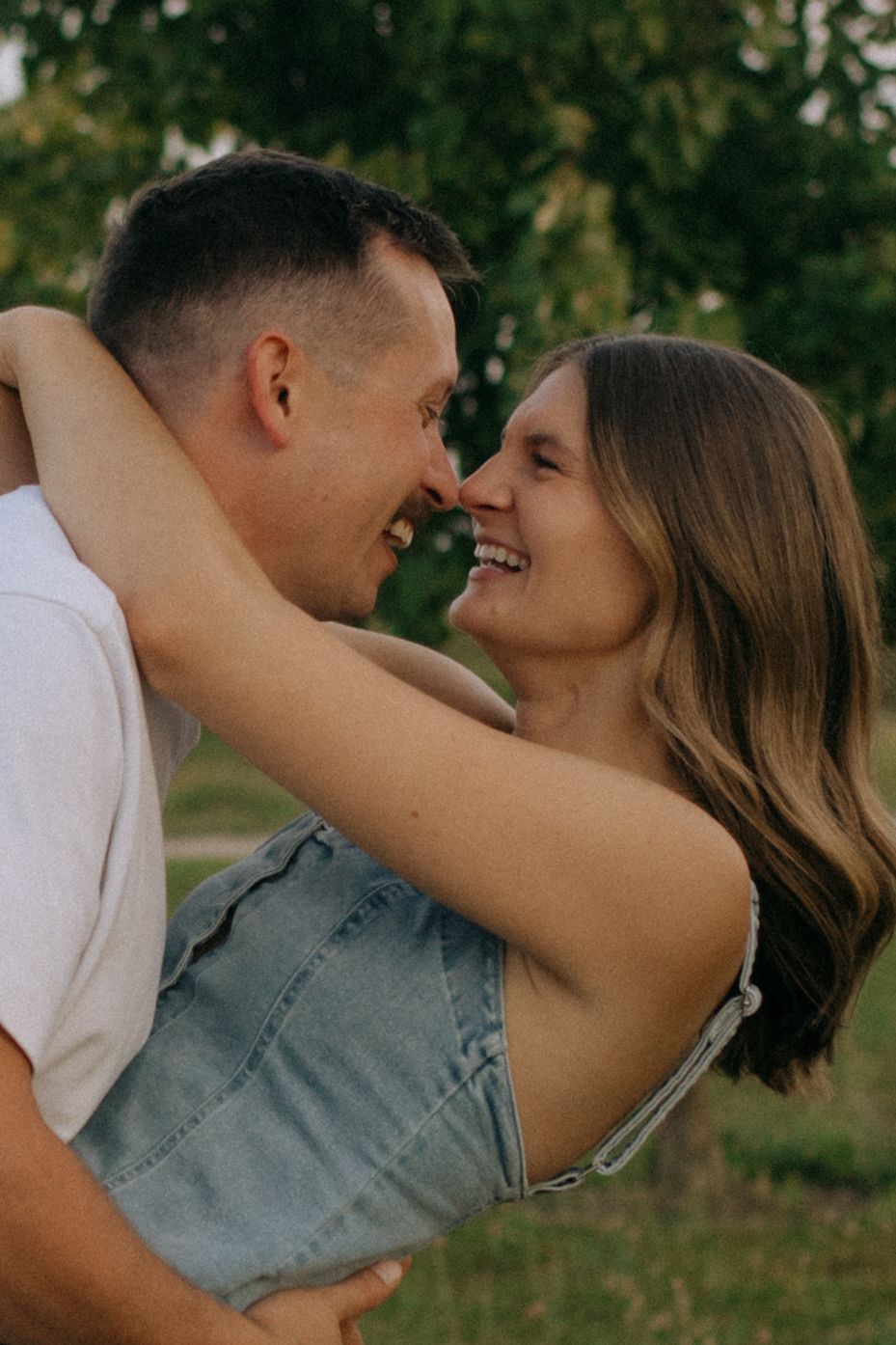 A couple shares an intimate moment outdoors during golden hour photography.