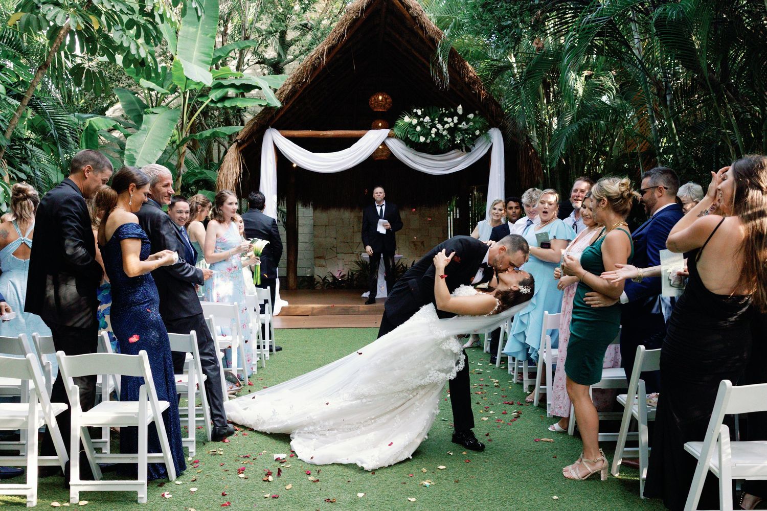 Outdoor garden wedding ceremony setup with white chairs and natural greenery.