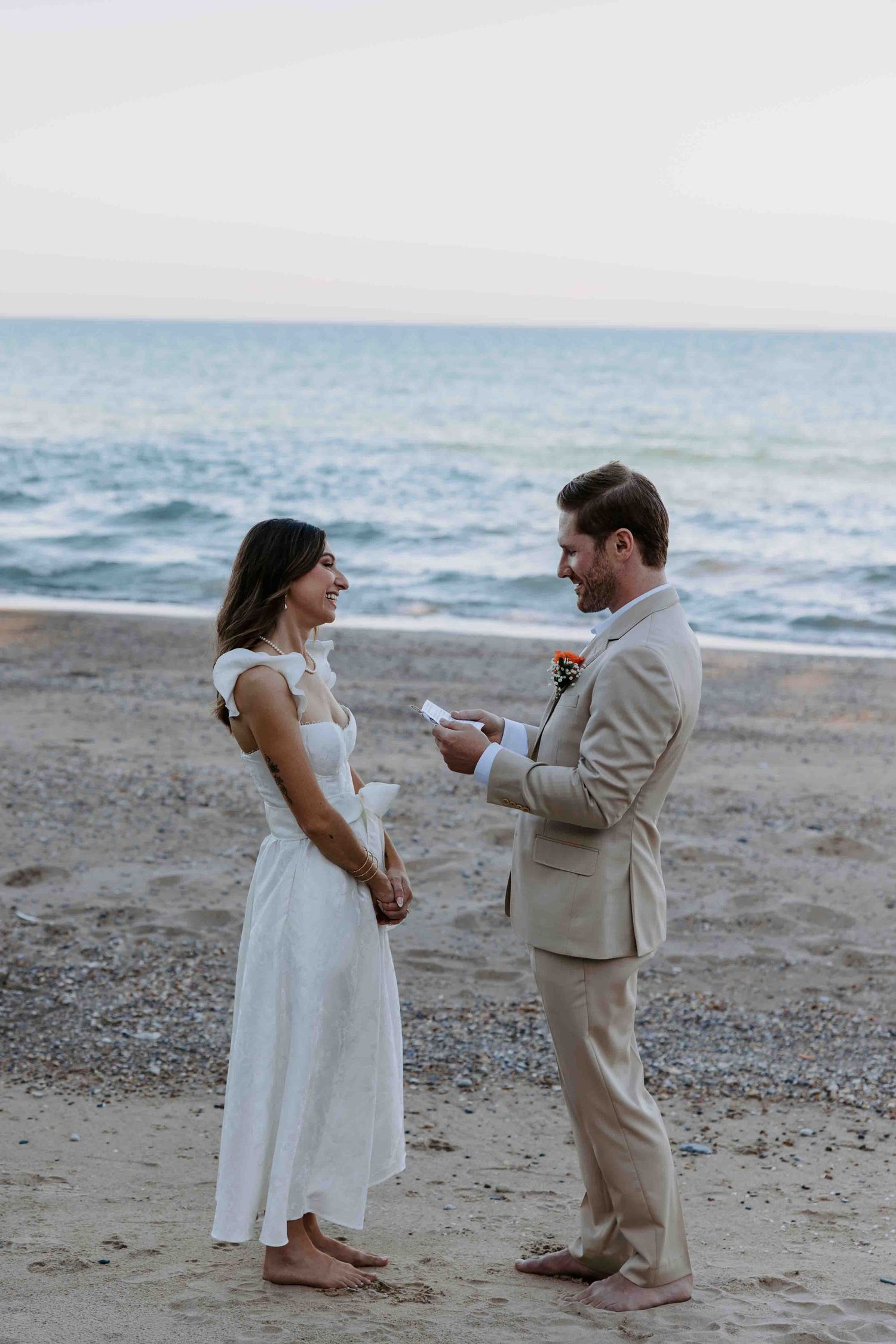Couple exchanging vows during beach wedding ceremony at sunset.