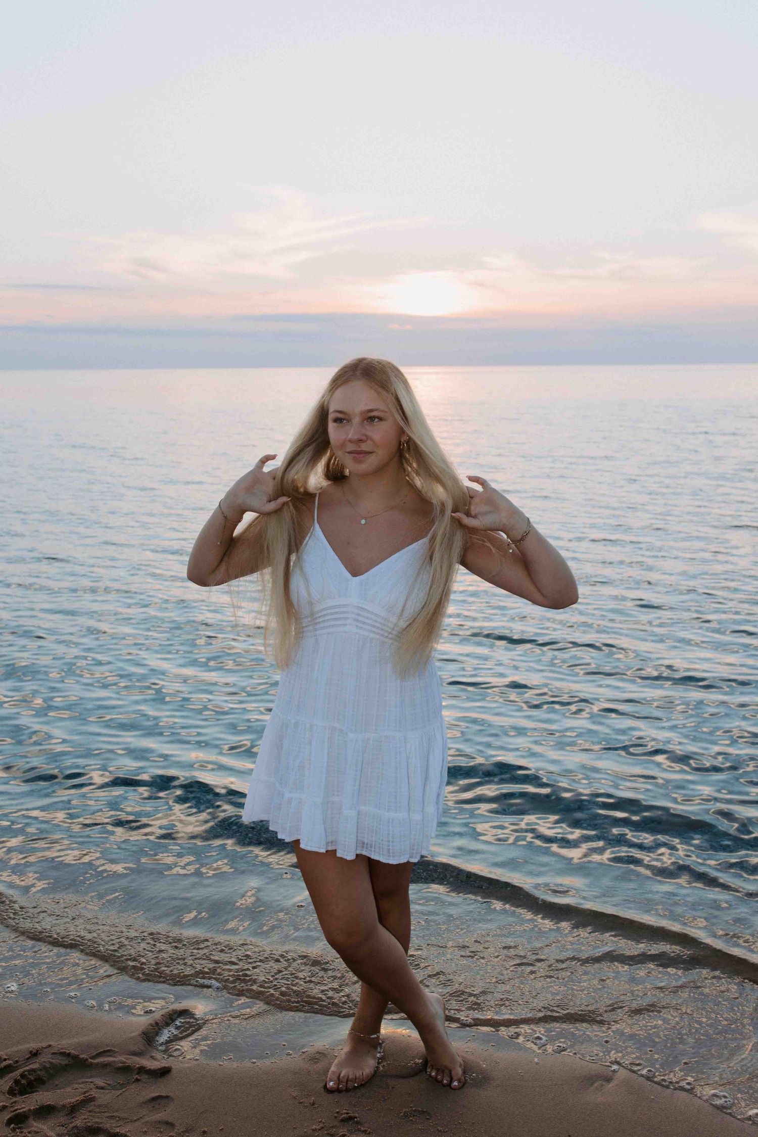 Playful poses on a sandy beach with someone wearing a white summer dress during golden hour.
