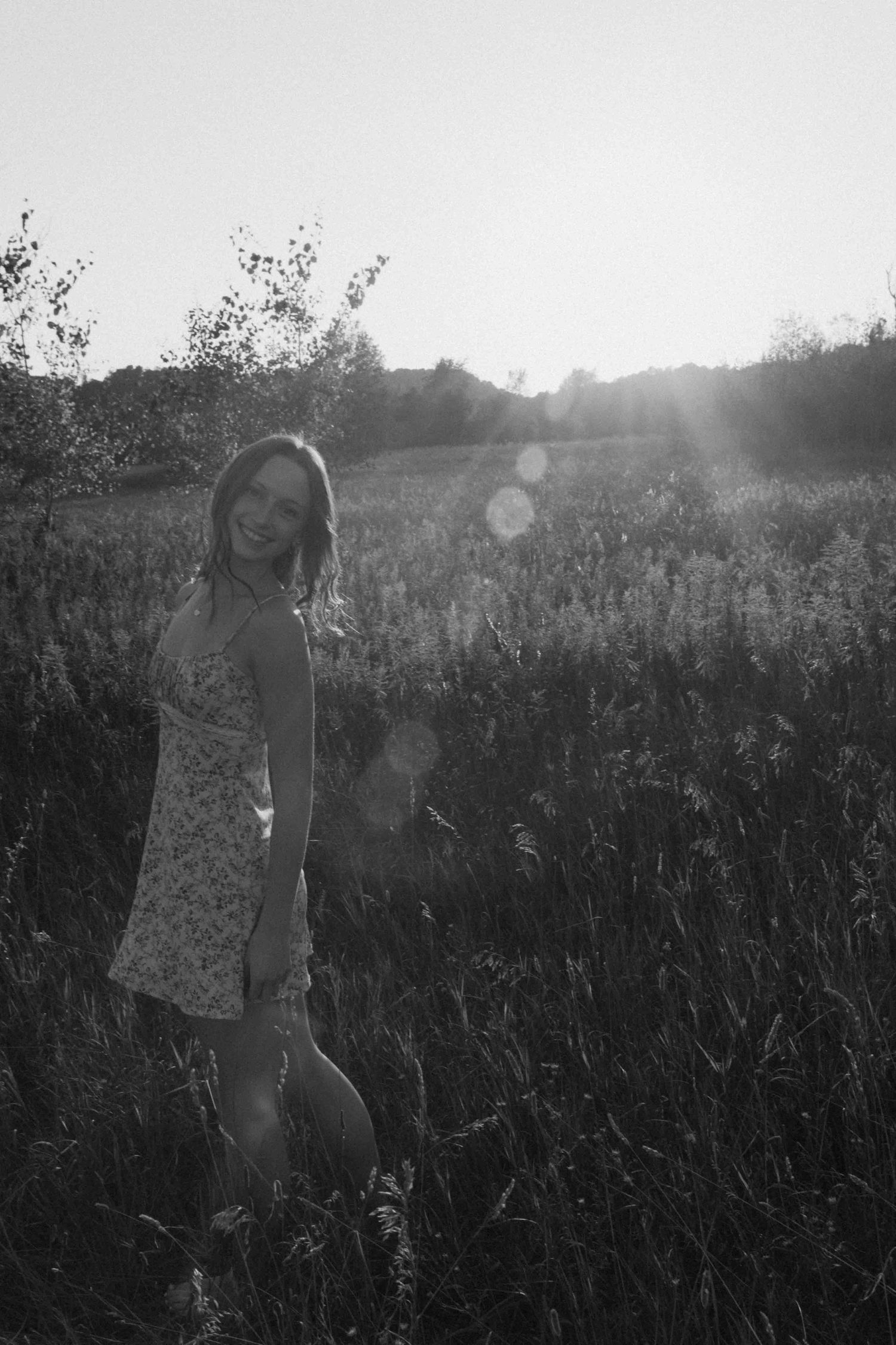 Artistic black and white photo of someone walking through a misty field at sunset.