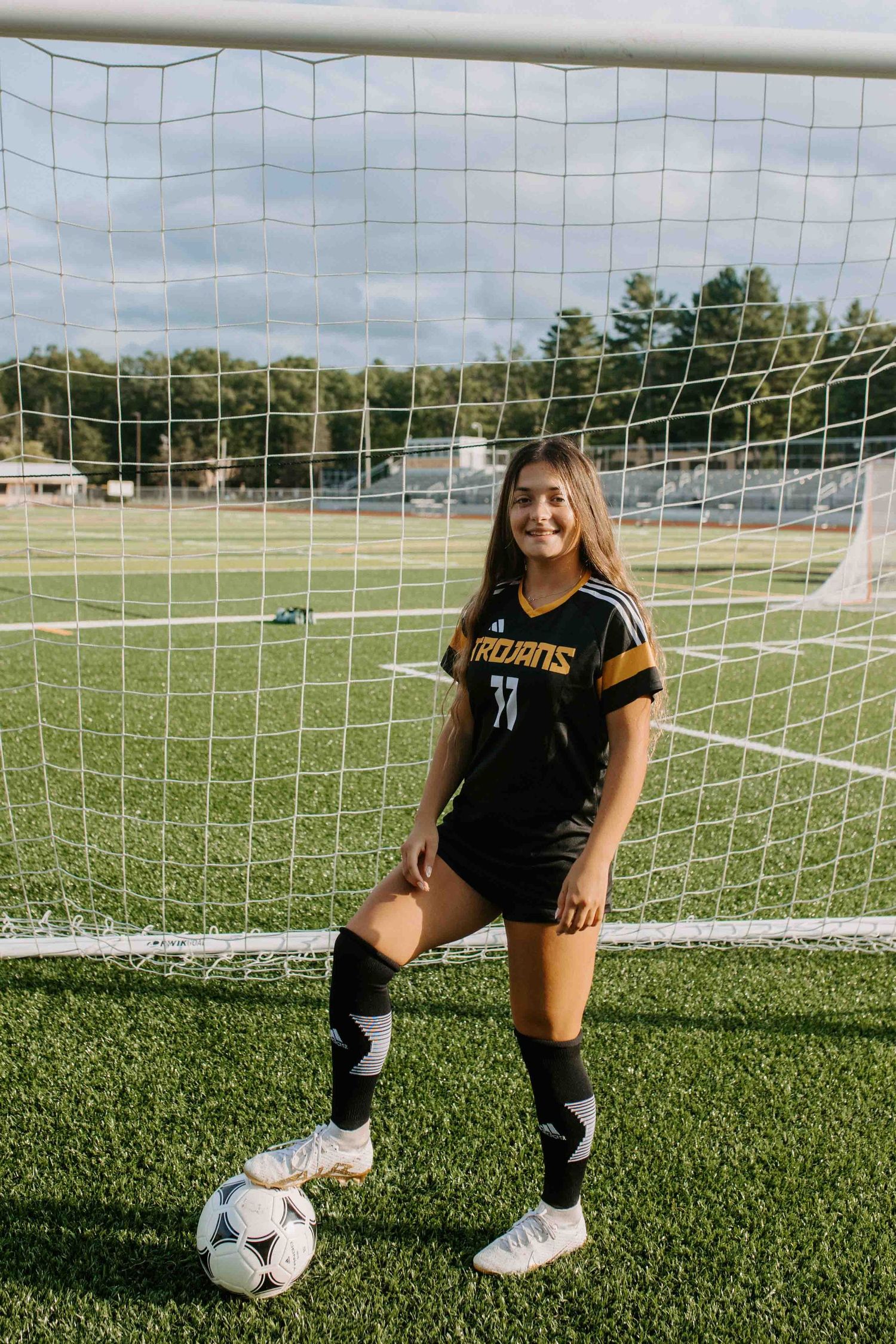 Soccer player in Trojans uniform practicing near goal post.