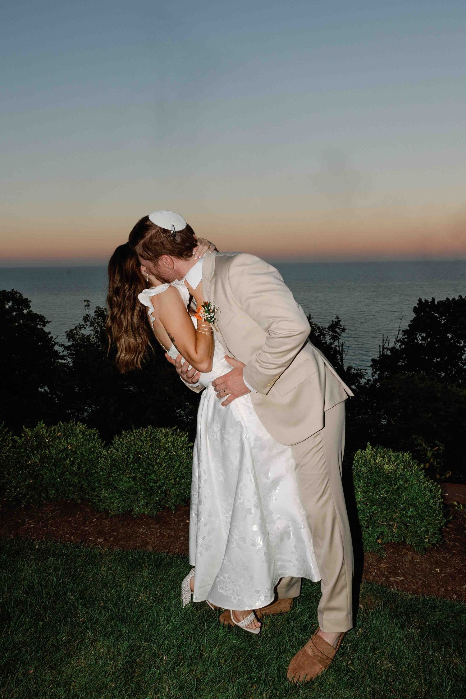 A romantic dip pose during sunset with the ocean in the background.