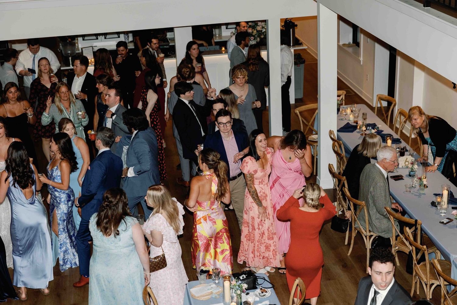 Panoramic view of wedding guests mingling and socializing at an indoor venue.