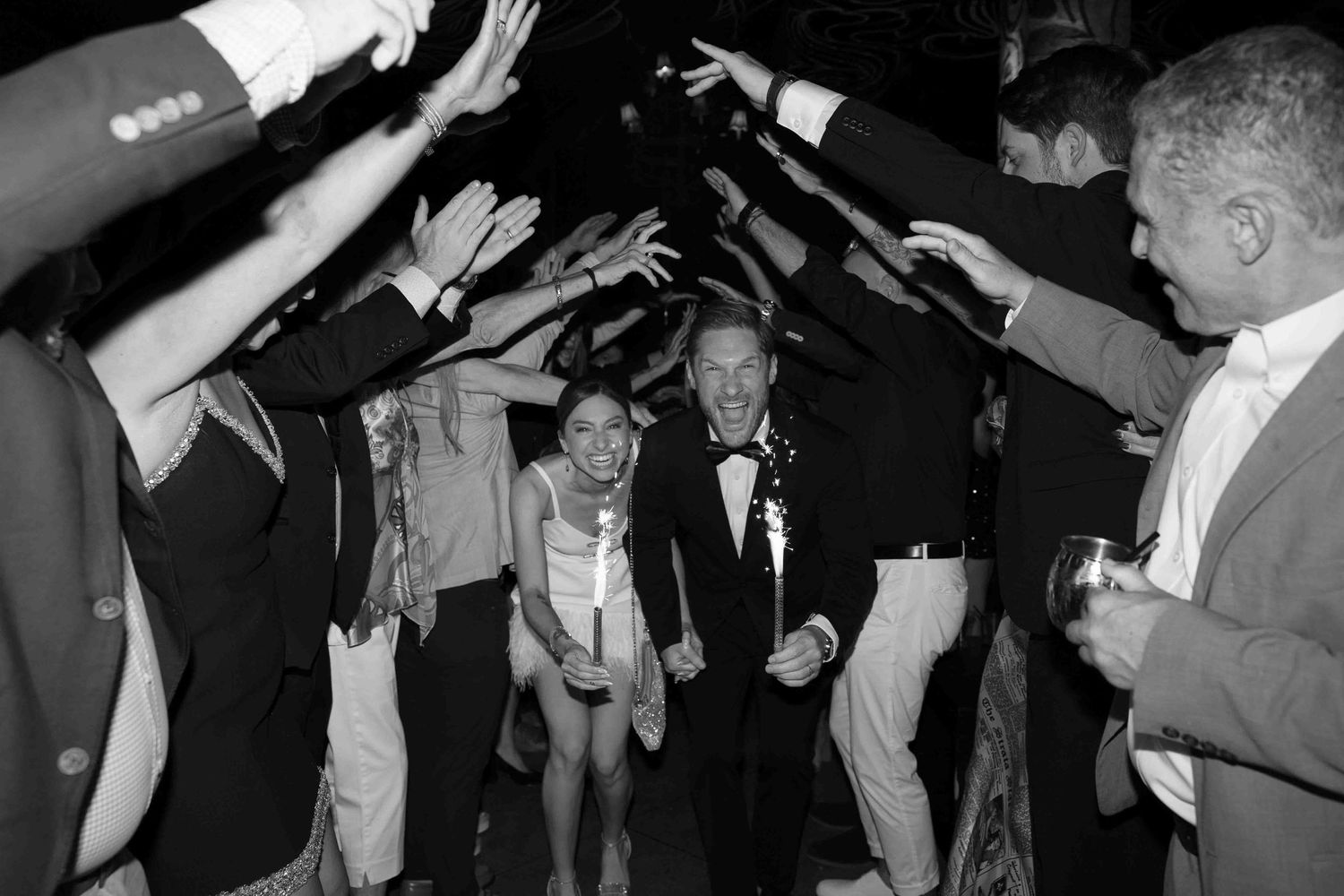 Party guests dance in formal attire at a dimly lit reception venue.