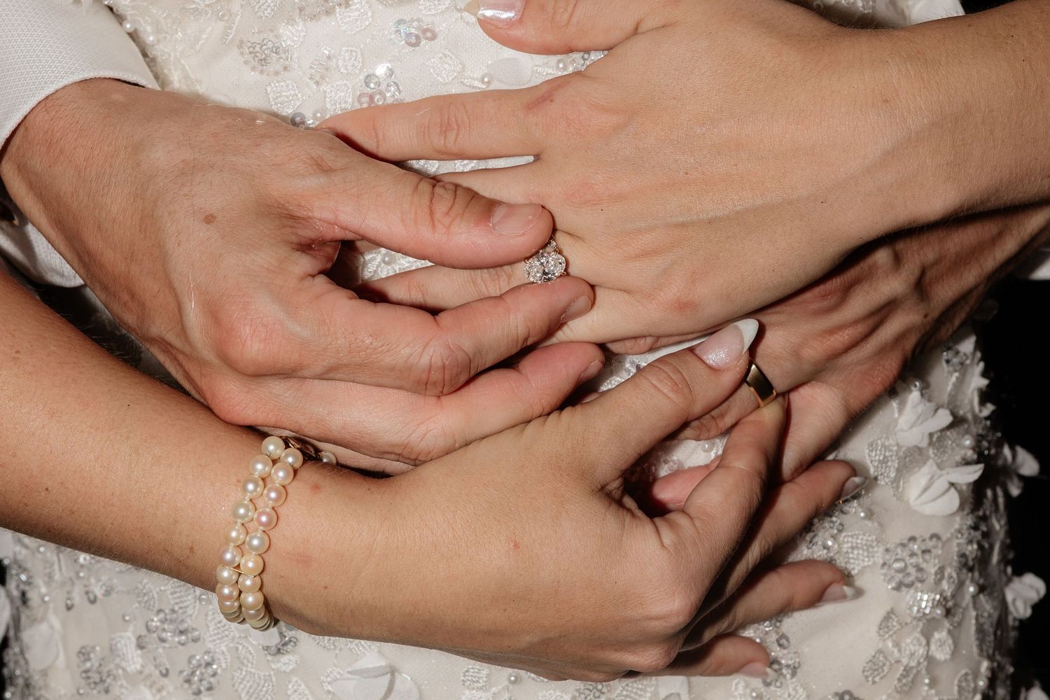 Close-up of hands with wedding rings and jewelry.