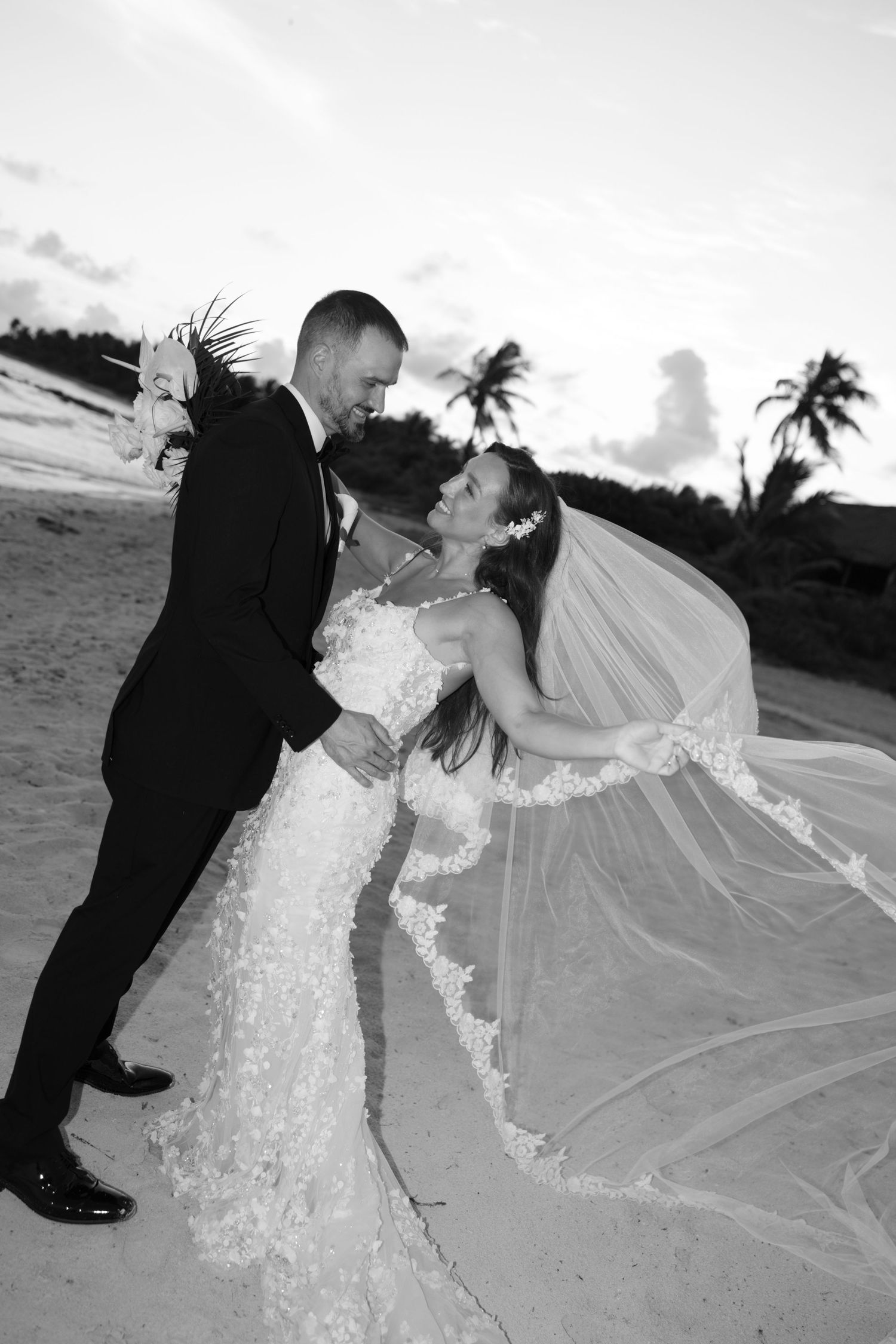 Romantic beachside wedding portraits featuring a detailed lace dress and flowing veil.