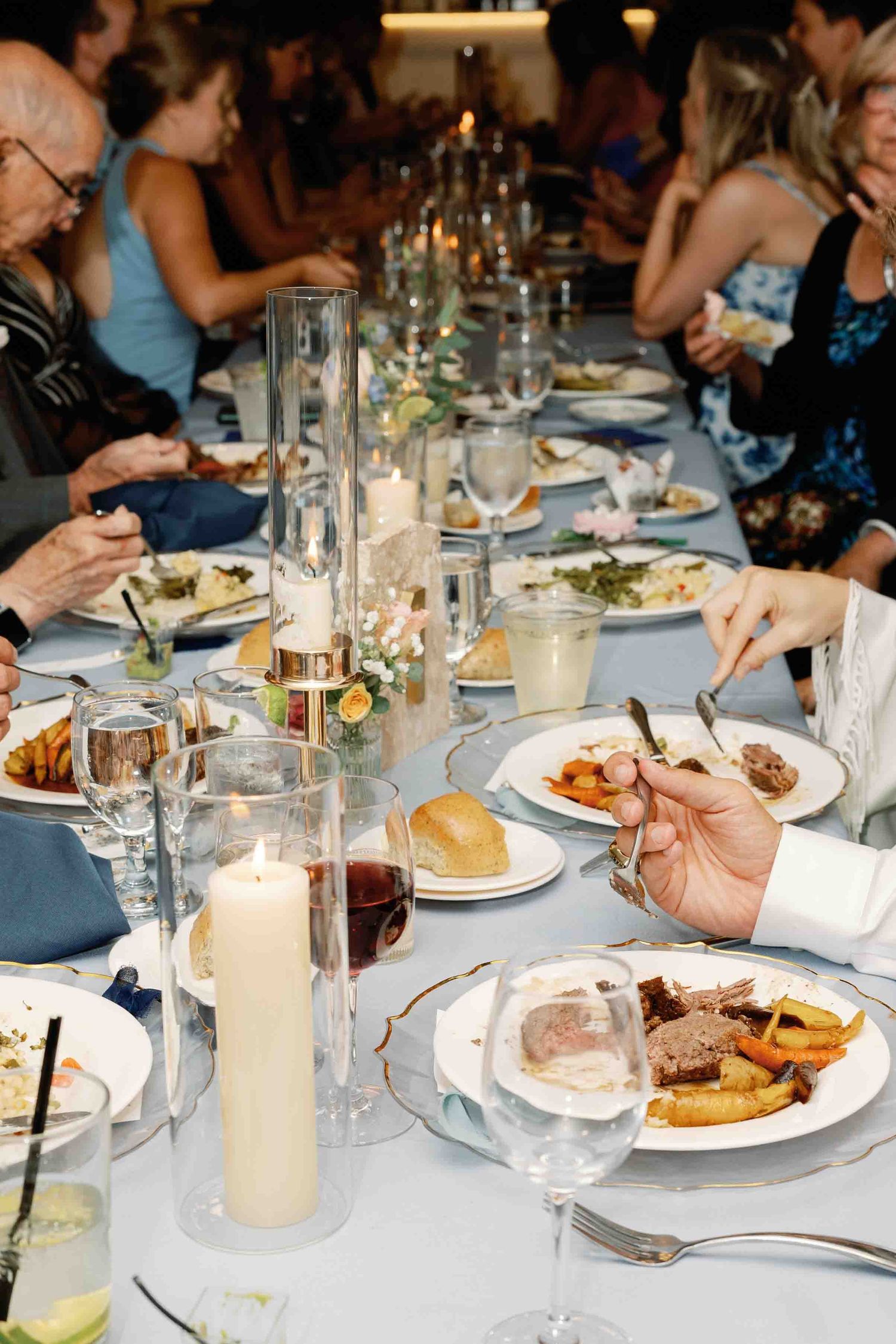 Elegant wedding reception table settings with lit candles and plated meals.