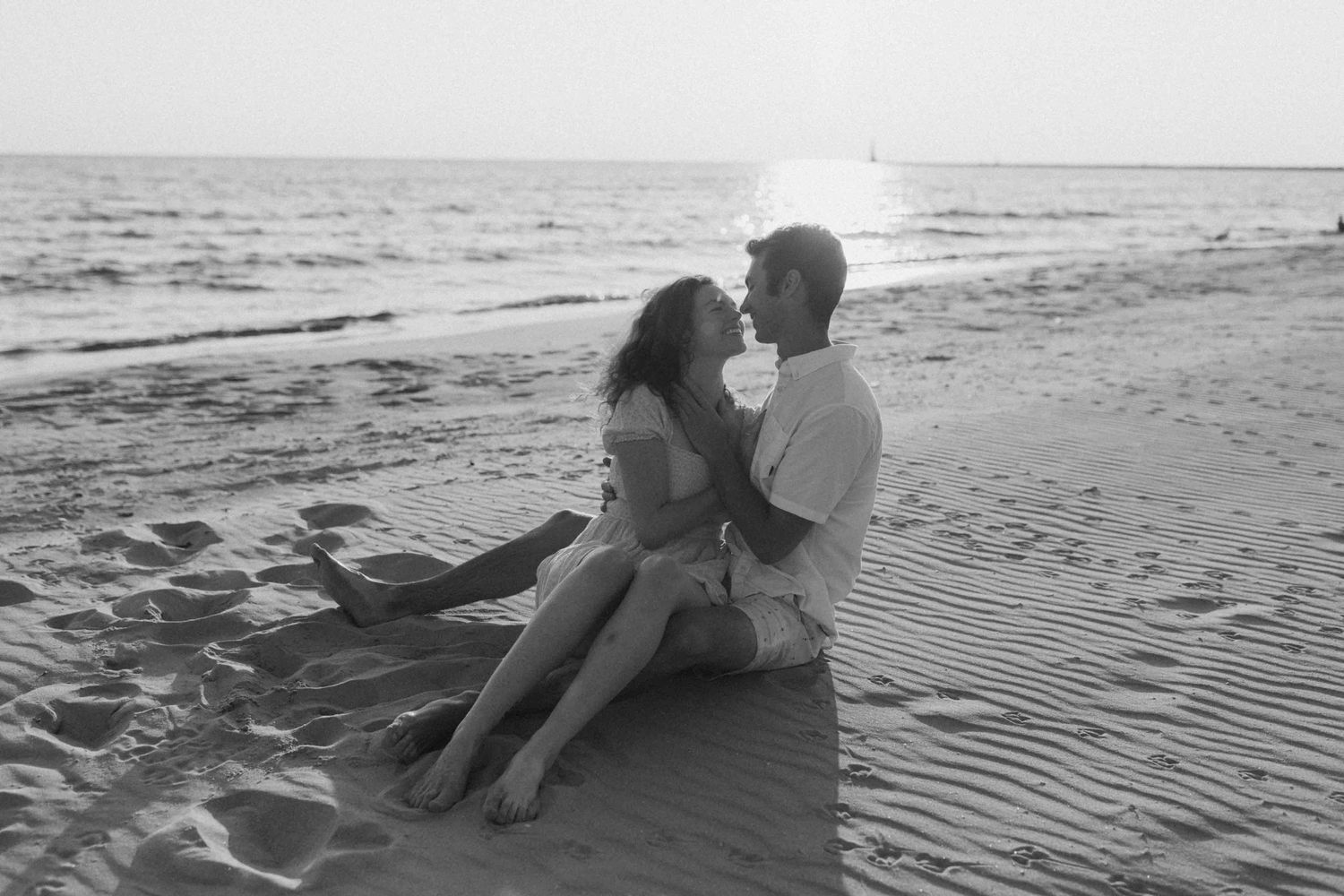 Couple relaxing together on sandy beach at sunset.