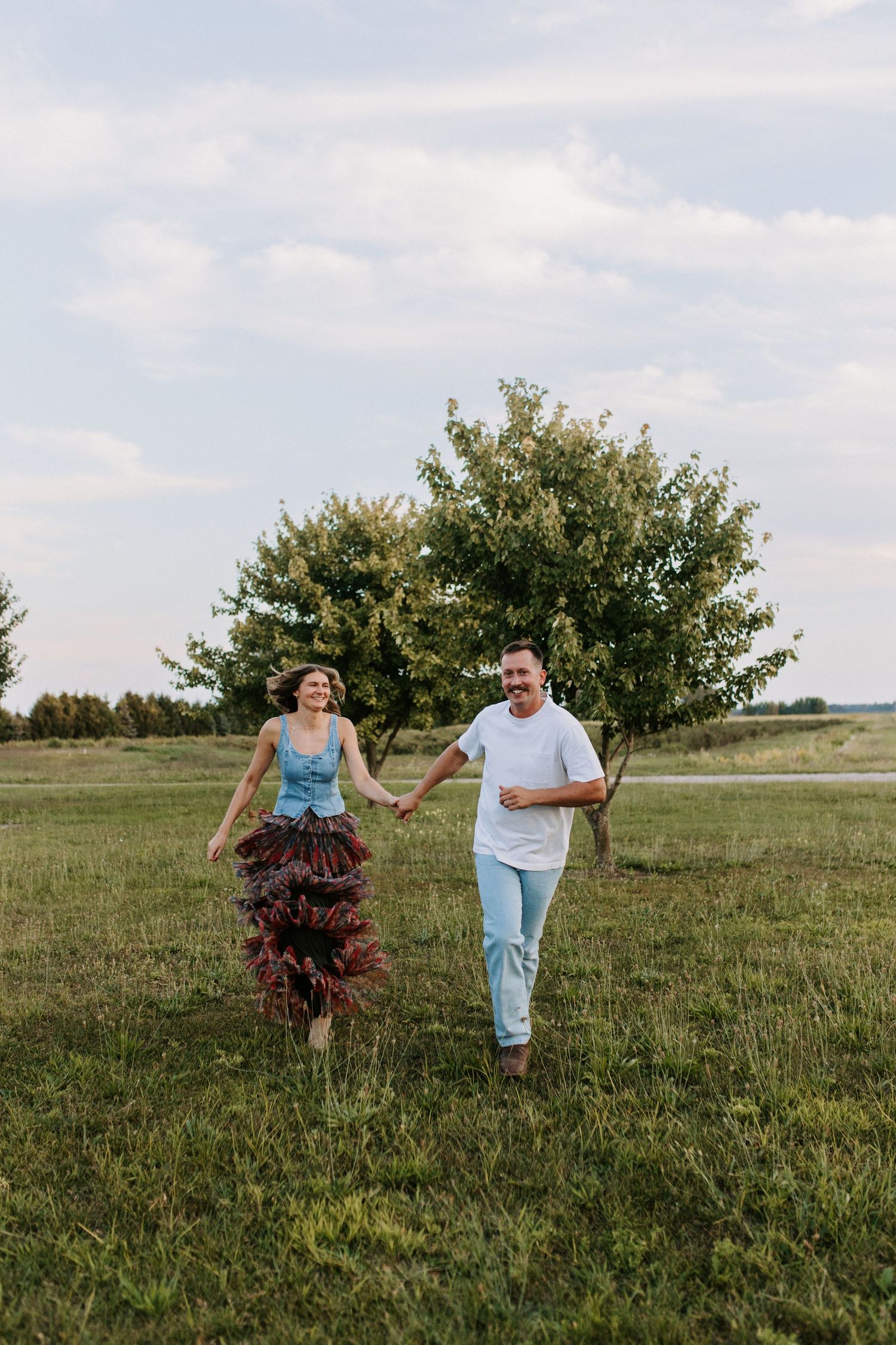 Joyful couple running and playing in a grassy field at sunset.