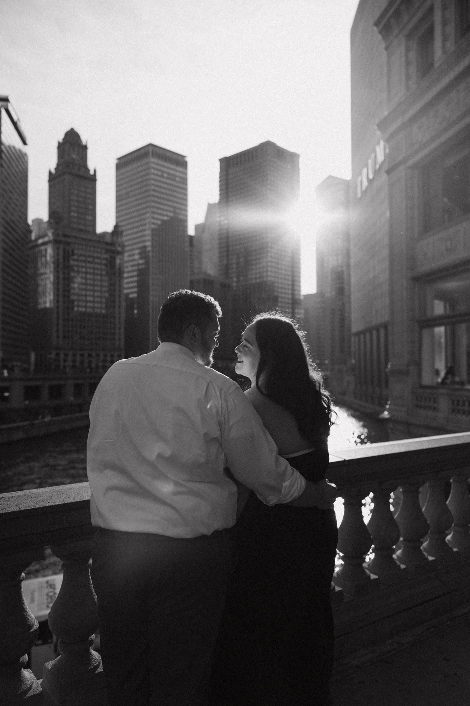 A silhouetted couple stands against a cityscape backdrop at sunset.