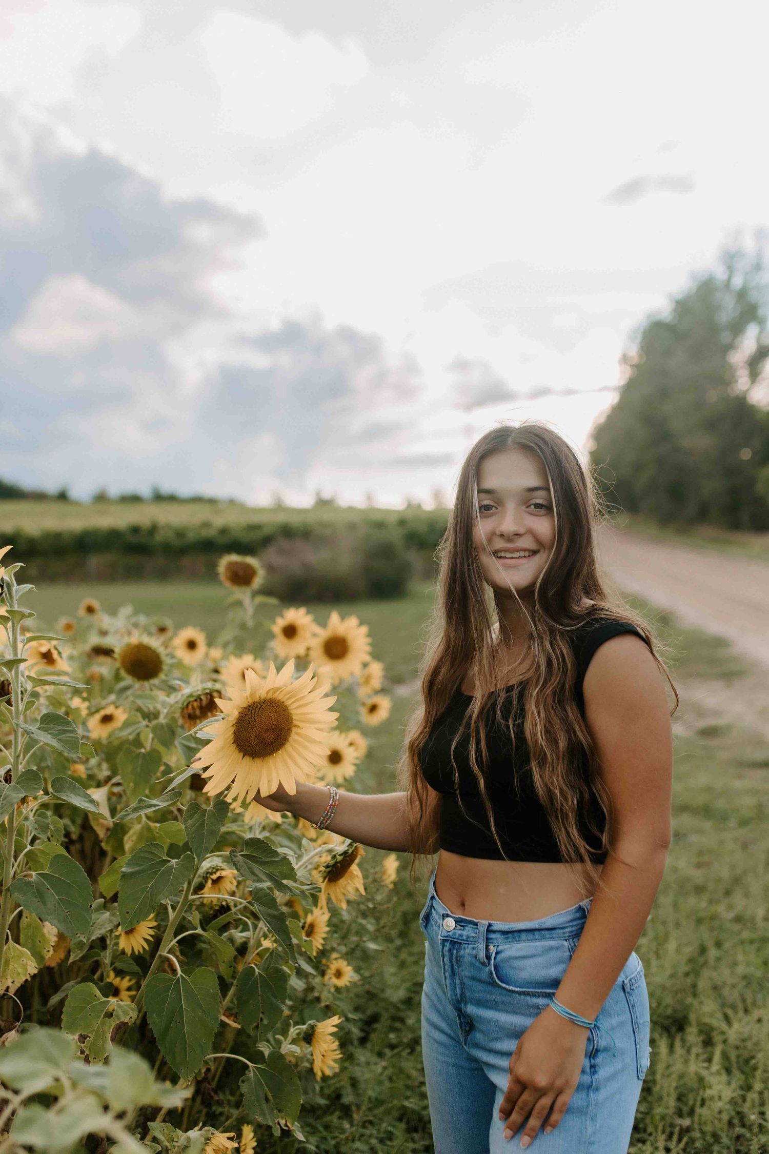 Summer portrait session among bright yellow sunflowers at sunset.
