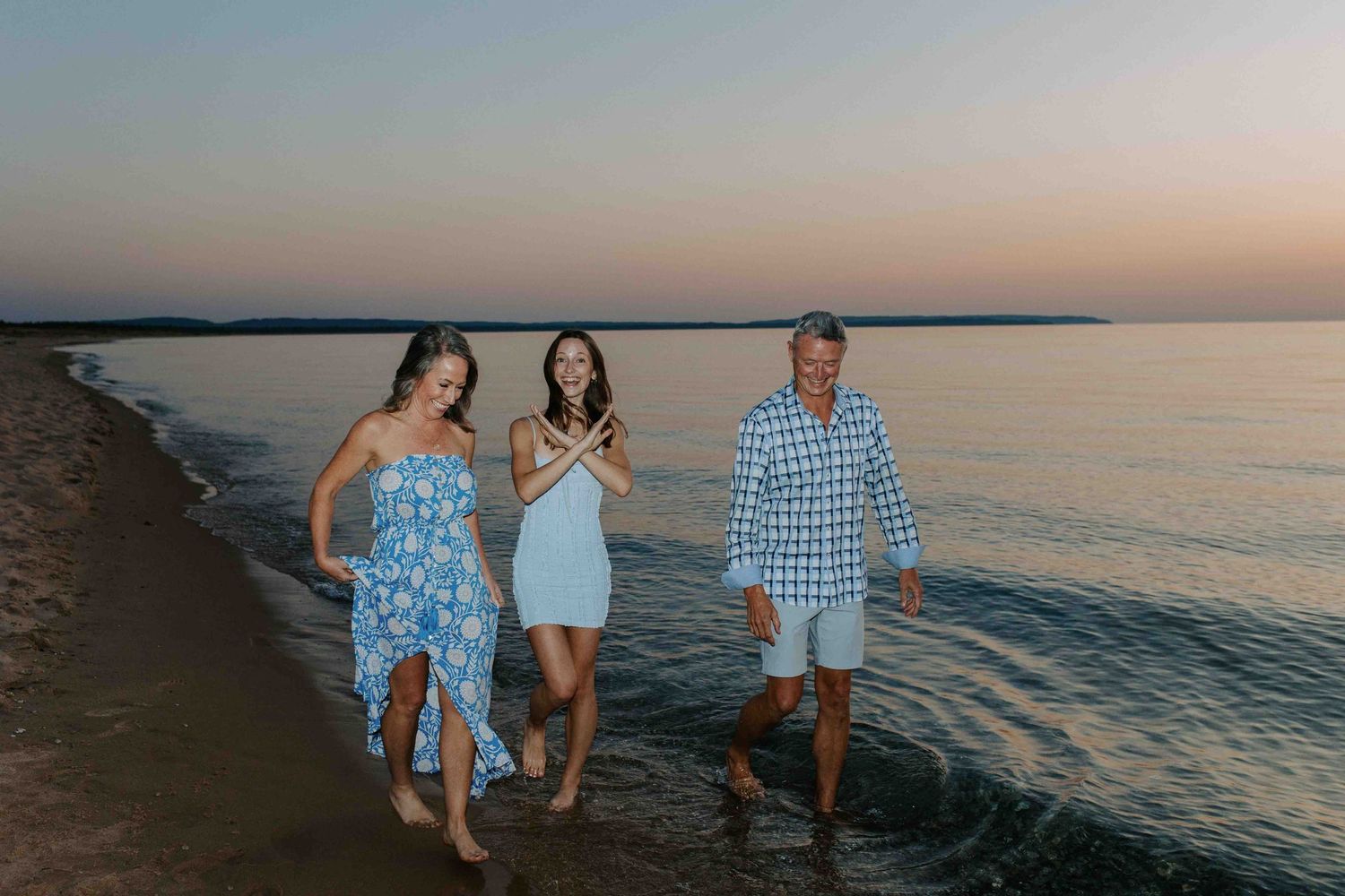 Friends enjoying a casual stroll on the beach at sunset wearing coordinated blue outfits.