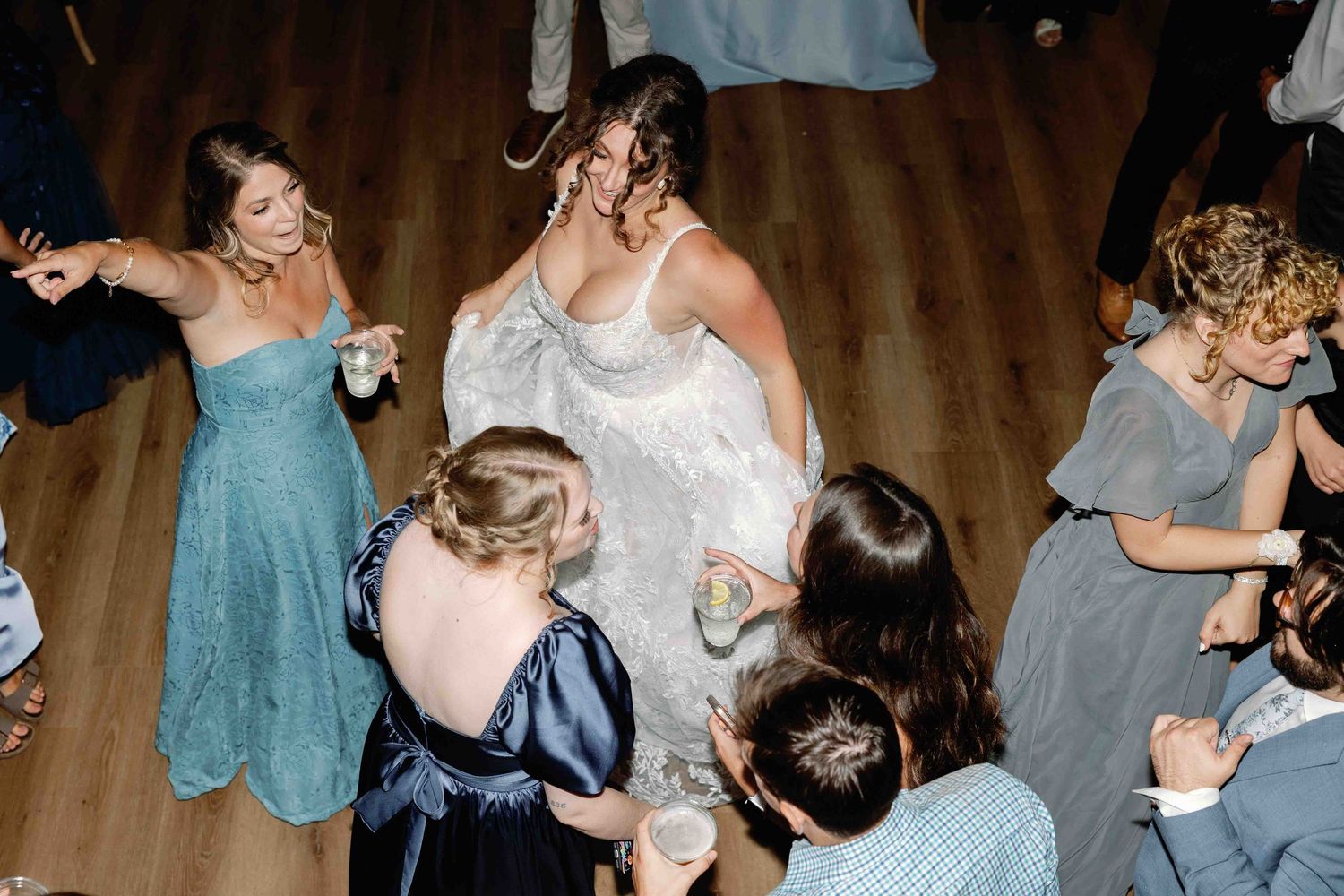 Wedding party members dance and celebrate on a wooden dance floor at evening reception.