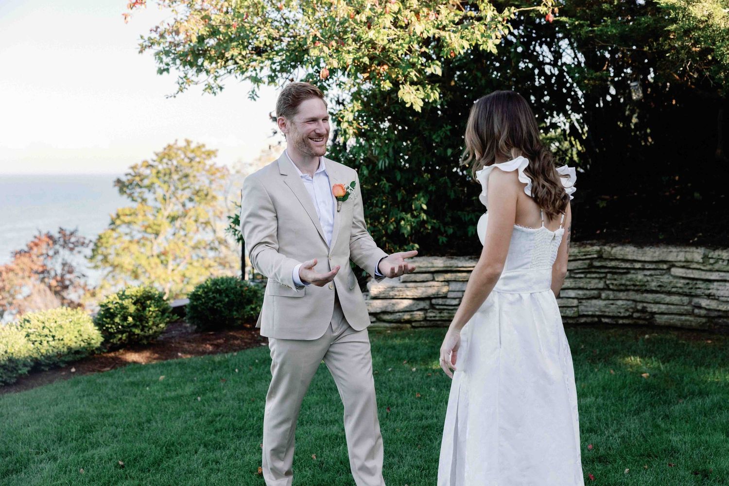 A couple dances together outdoors during golden hour at a sunset wedding celebration.