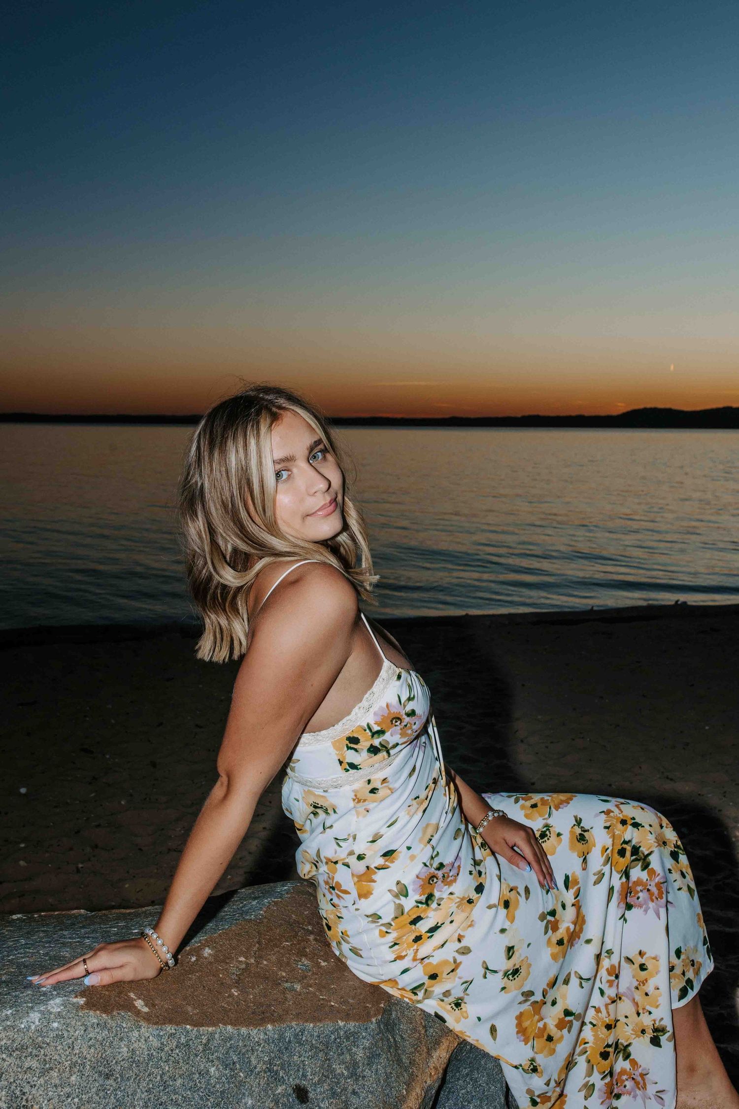 White floral dress against rocky beach setting during sunset.