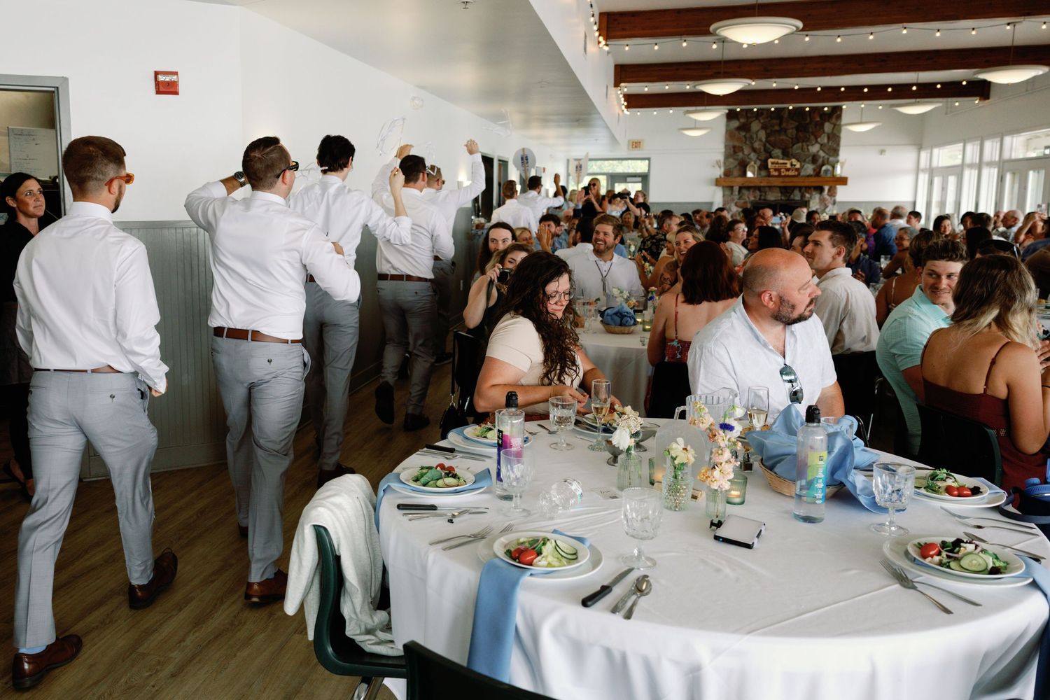 Wedding reception venue with tables set up for dining and guests mingling in a bright indoor space.