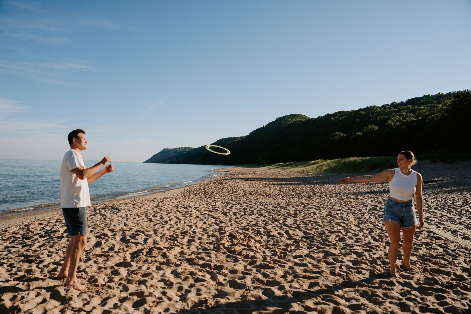 People walking on a vast sandy beach with coastal cliffs in the distance.