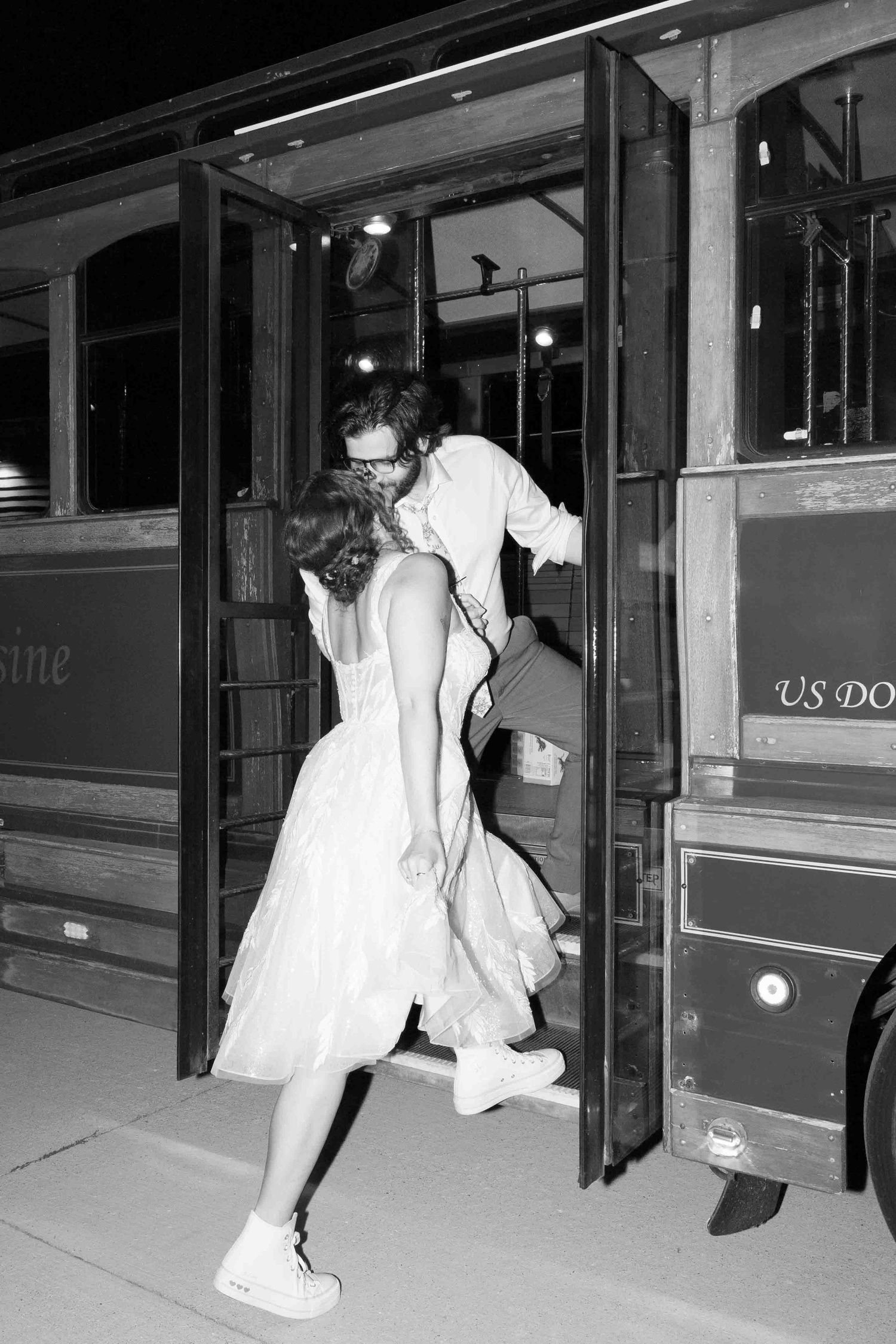 Night scene of people getting onto an illuminated vintage trolley.