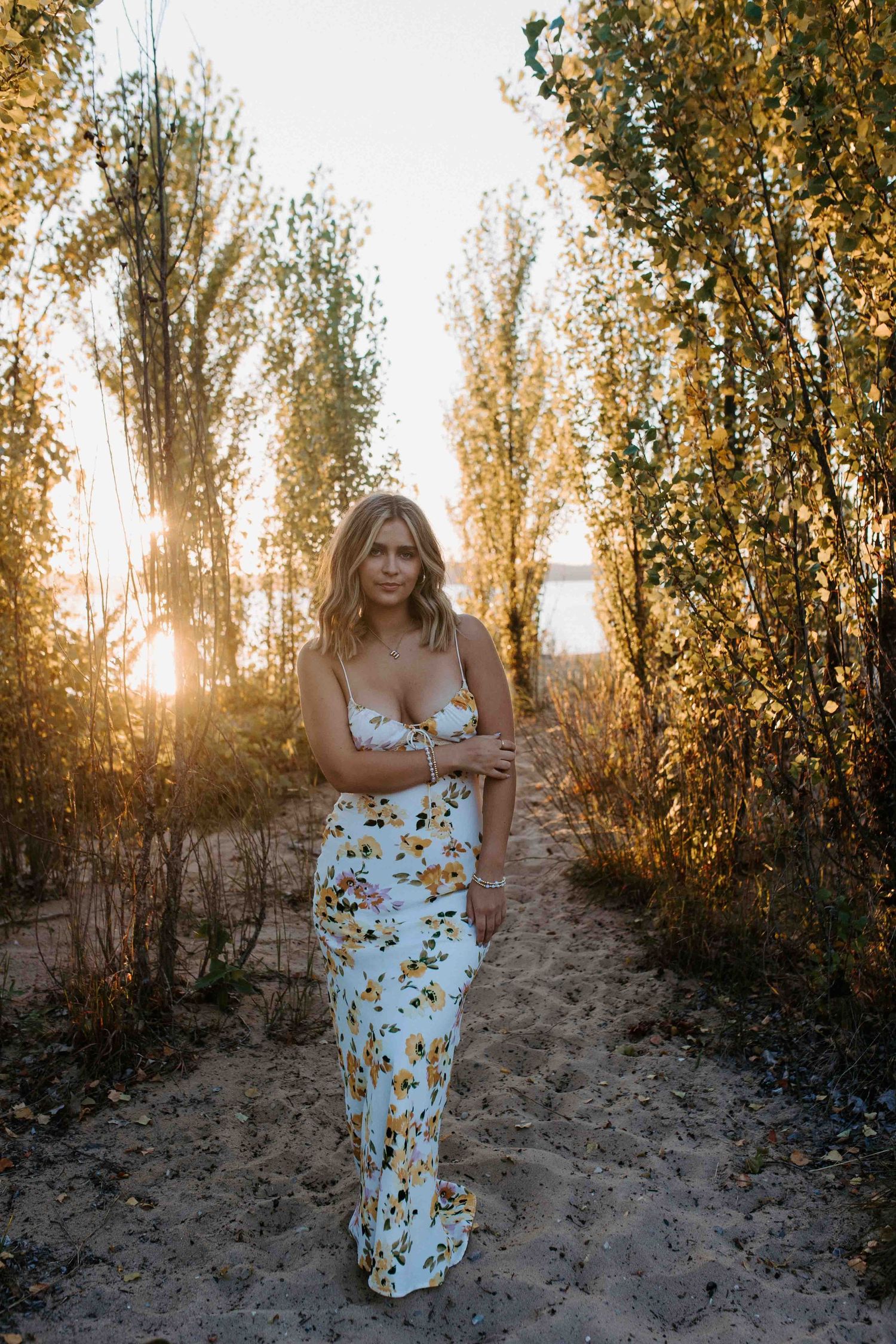 A summer evening photoshoot featuring a white floral dress against warm sunset lighting.