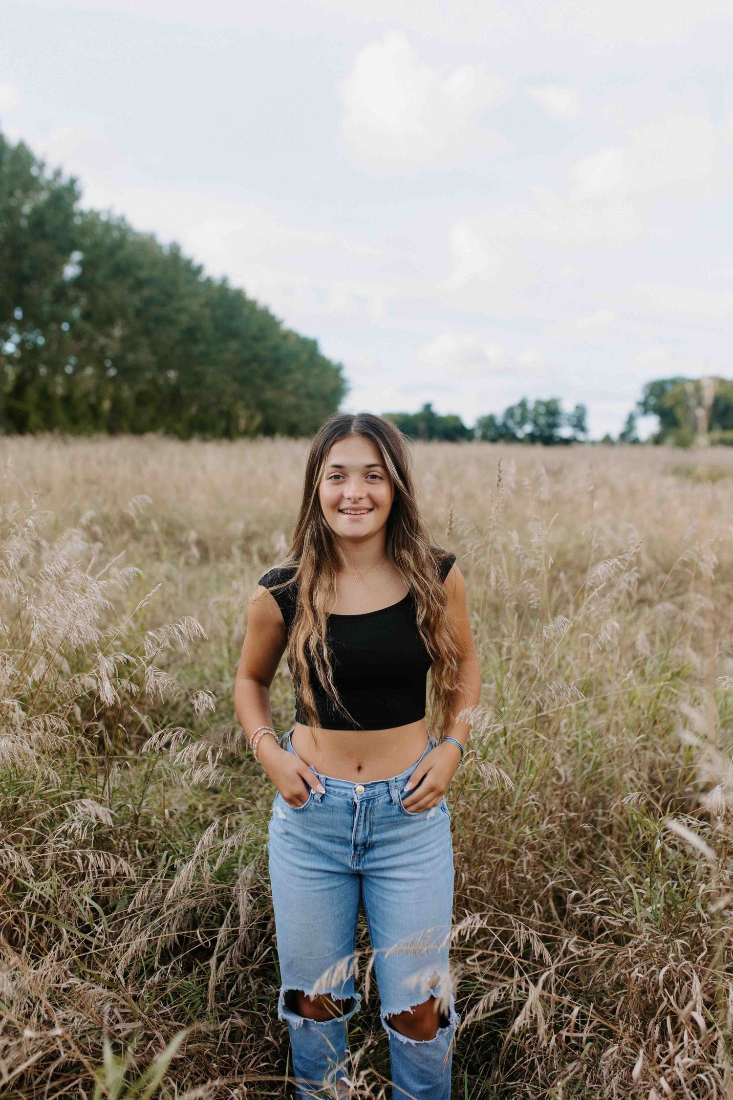 Casual outdoor portrait in a golden field wearing ripped jeans and black top.