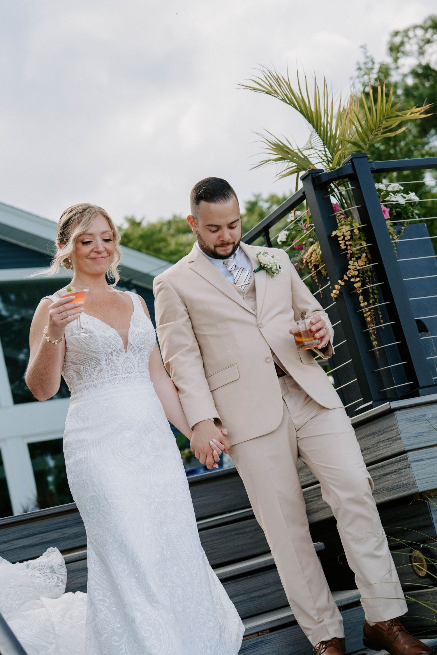 Newlyweds in white dress and tan suit share playful moments on an outdoor deck.