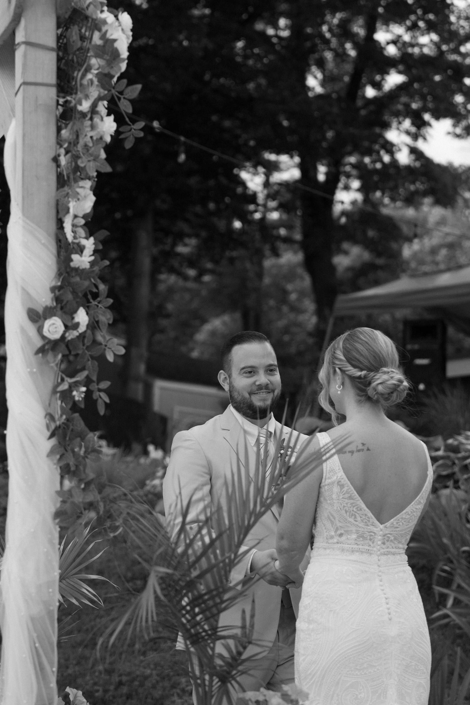 Wedding ceremony moments captured under decorated white columns with greenery.
