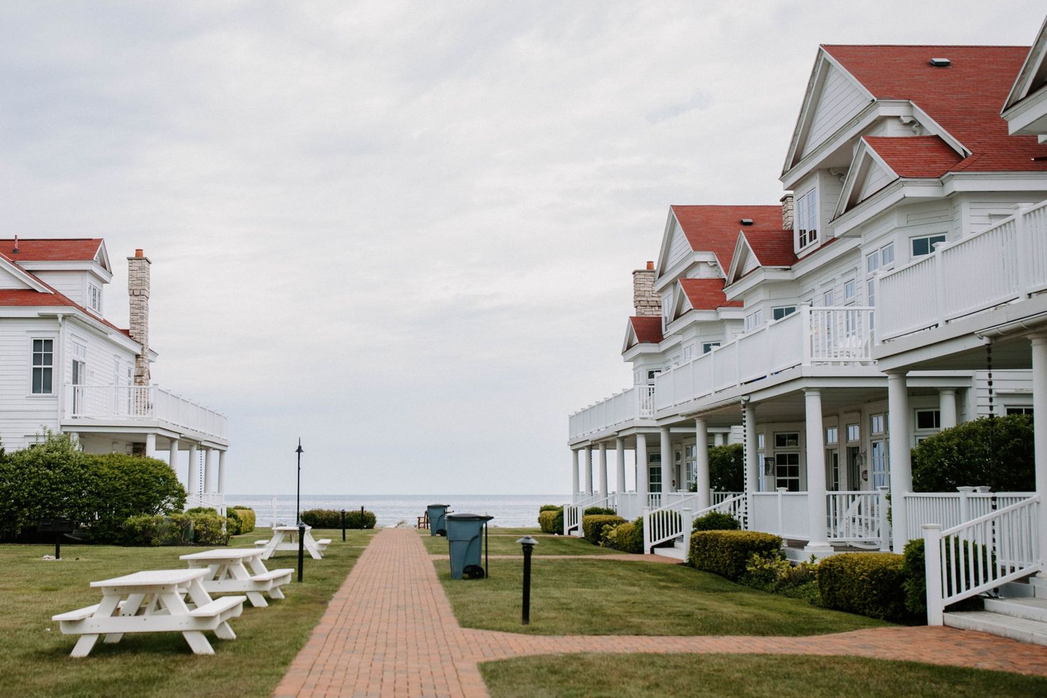Row of white coastal houses with red roofs overlooking the ocean on a sunny day.
