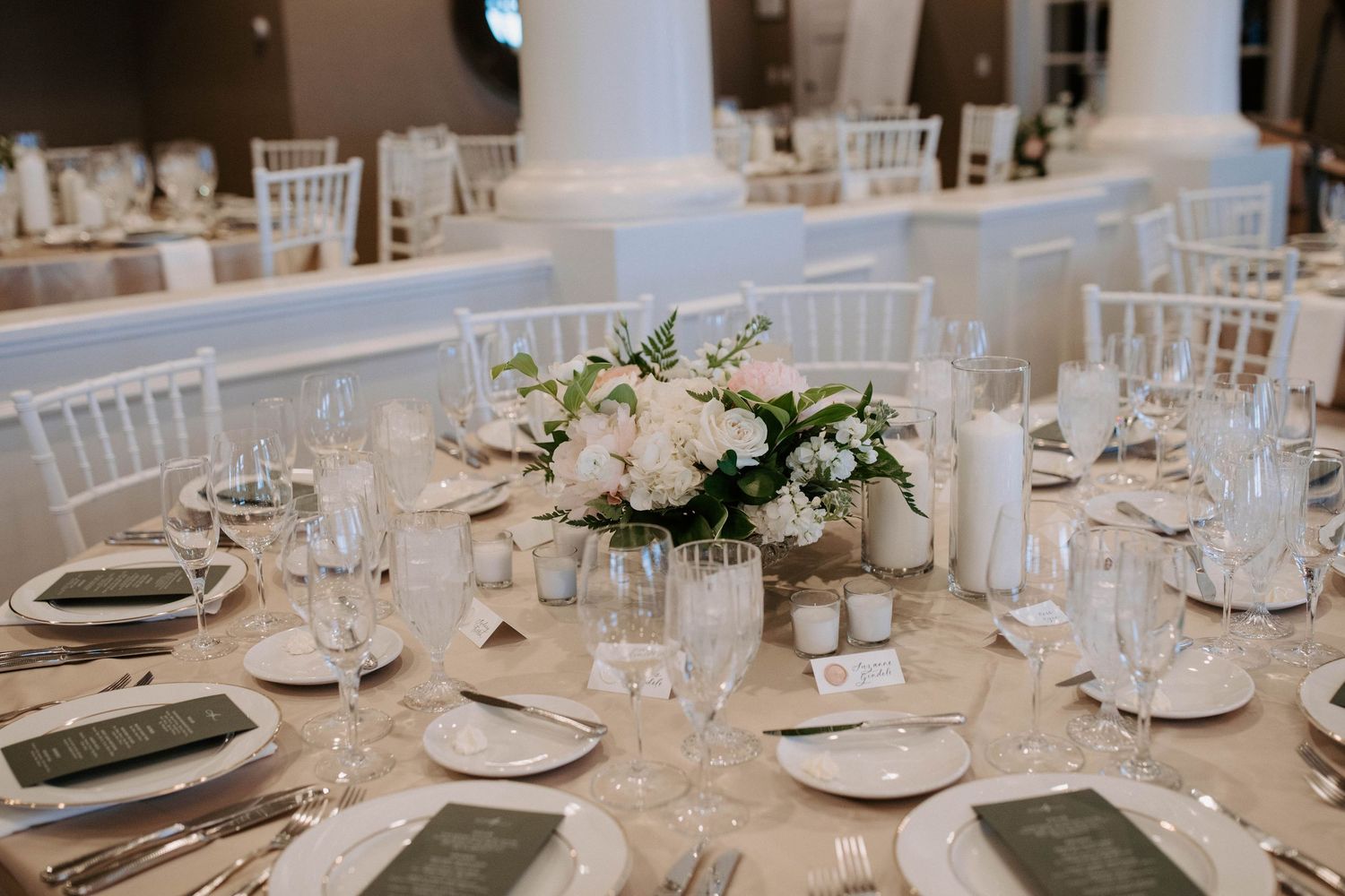 Elegant wedding reception table with white chiavari chairs and place settings.