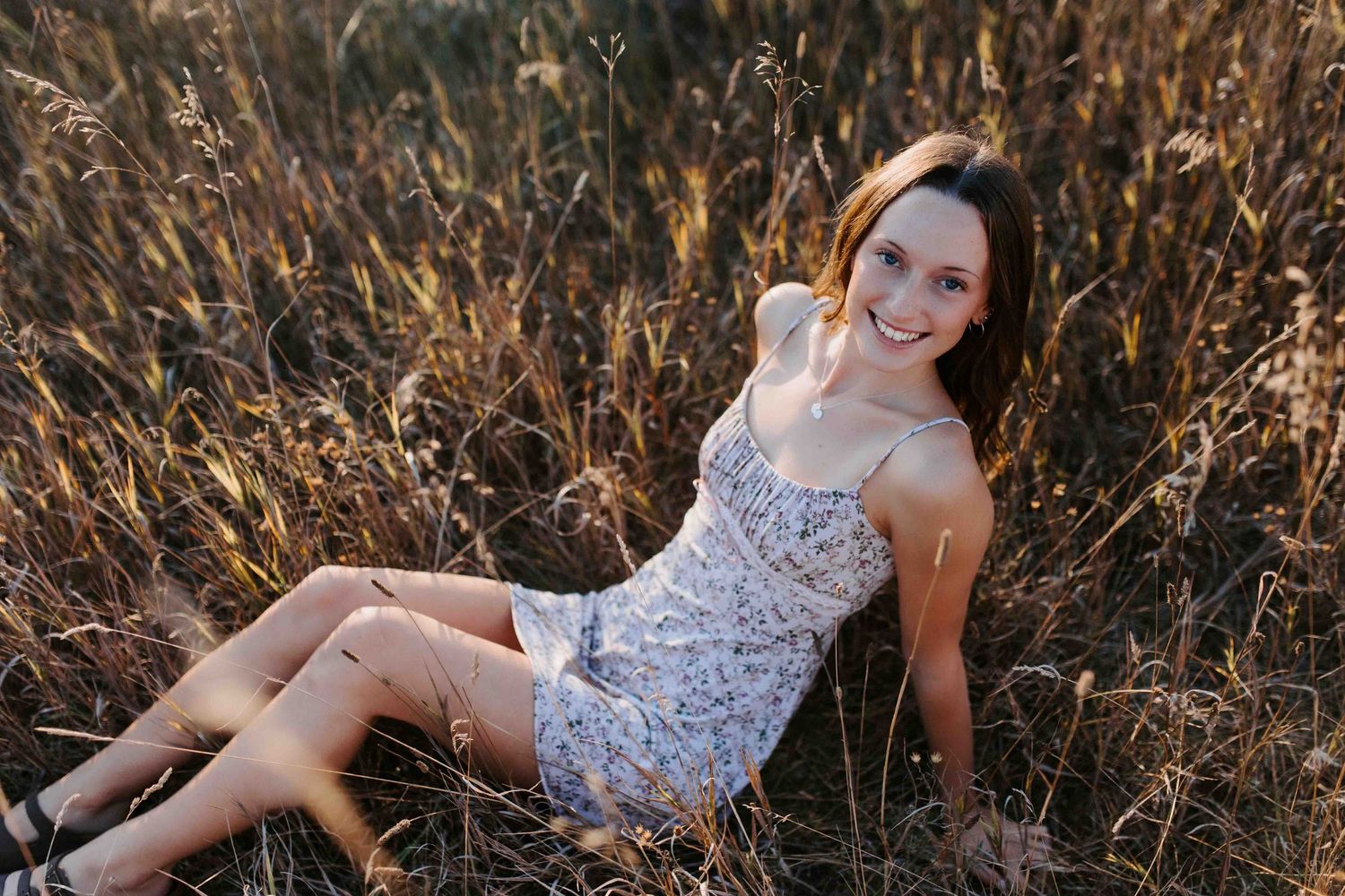 Relaxed outdoor portrait session in a natural field setting at sunset.