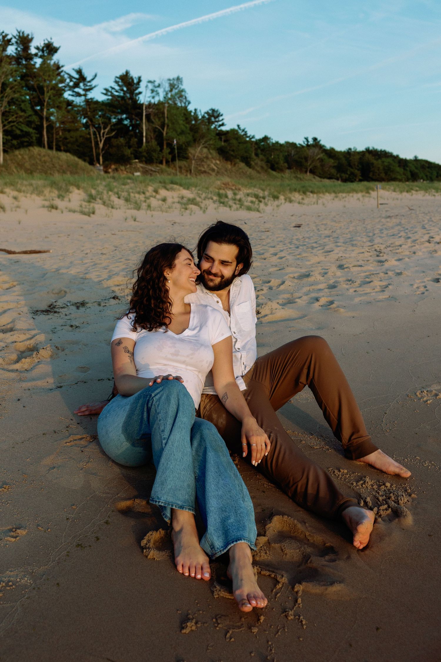 Couple relaxes together on sandy beach during golden hour.