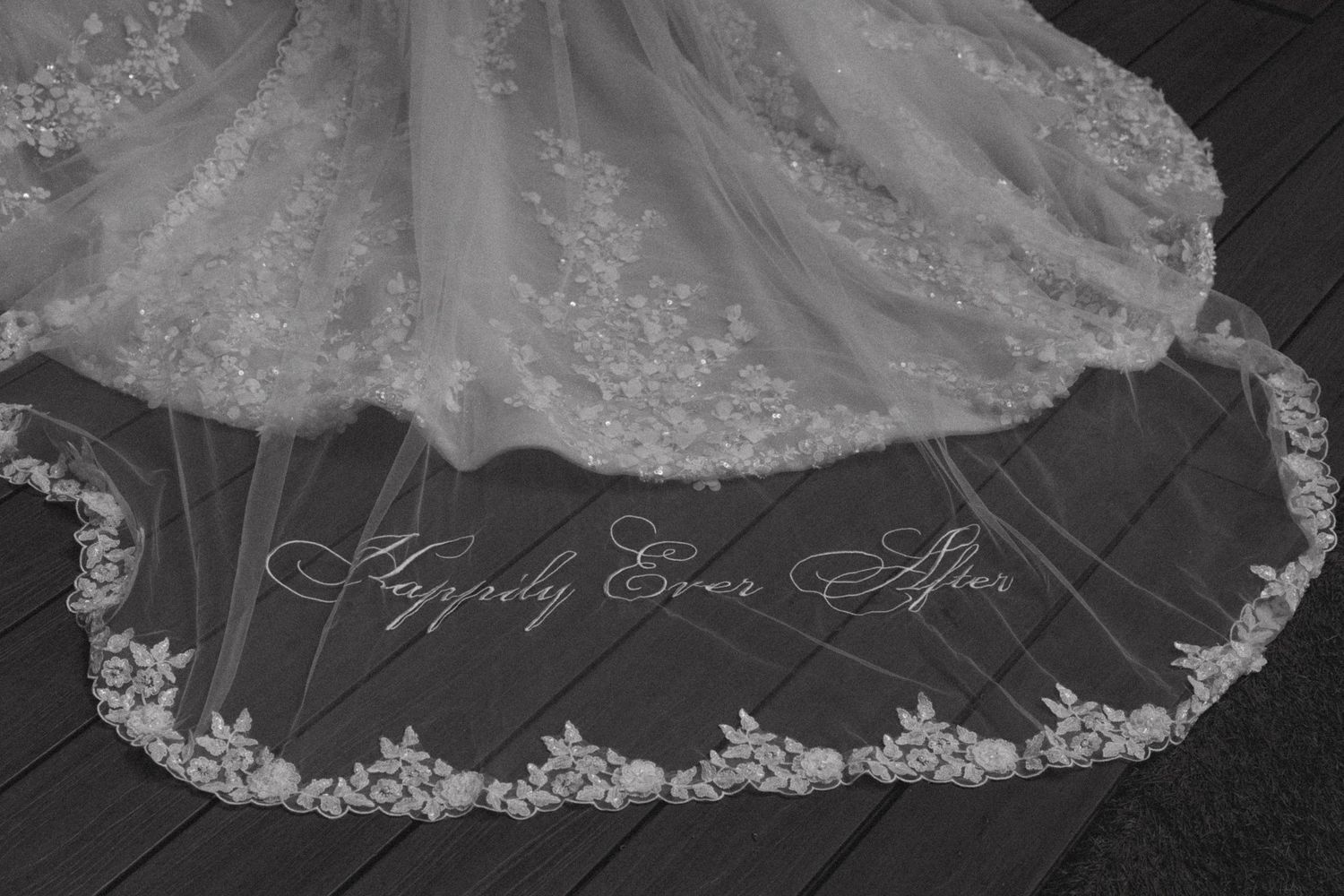 Detail shot of wedding dress hem with 'Happily Ever After' embroidered in elegant script.