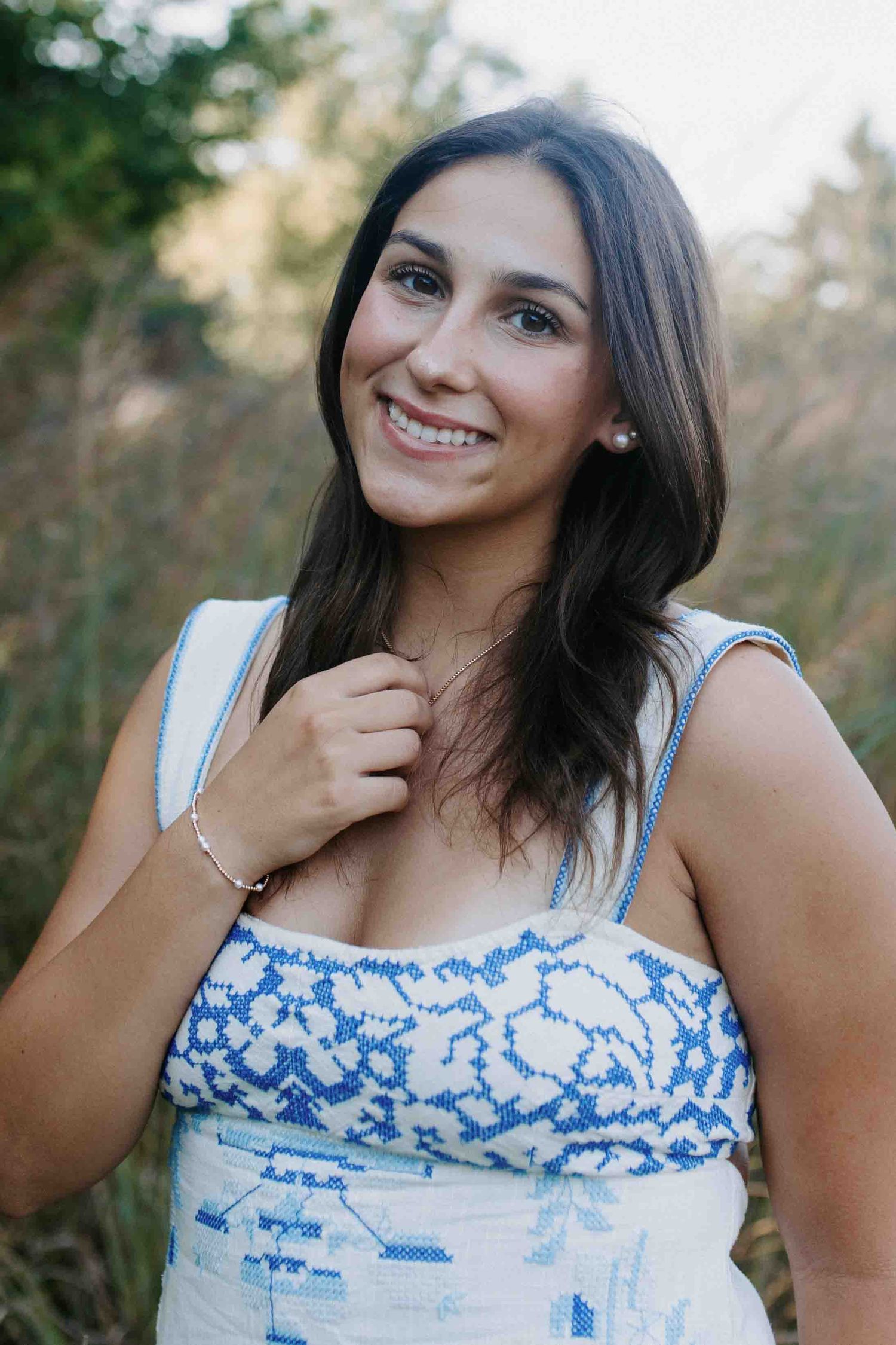 Close-up portrait wearing a blue and white patterned summer top against blurred nature background.