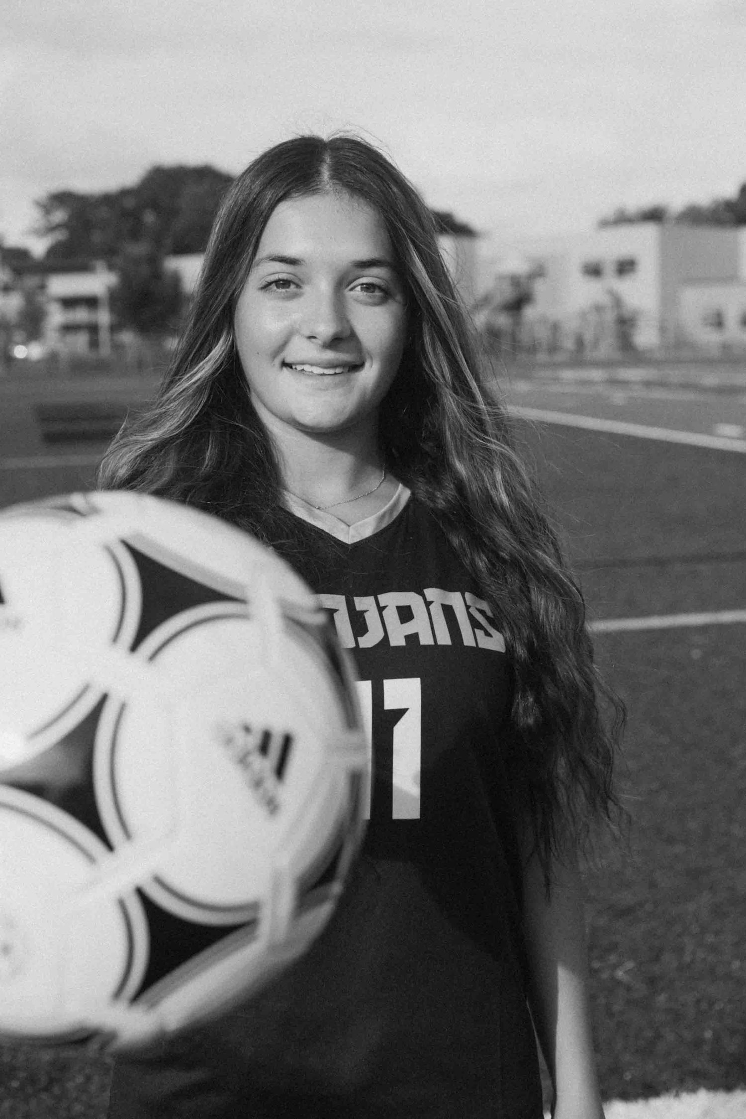 Black and white portrait of soccer player holding multiple soccer balls.
