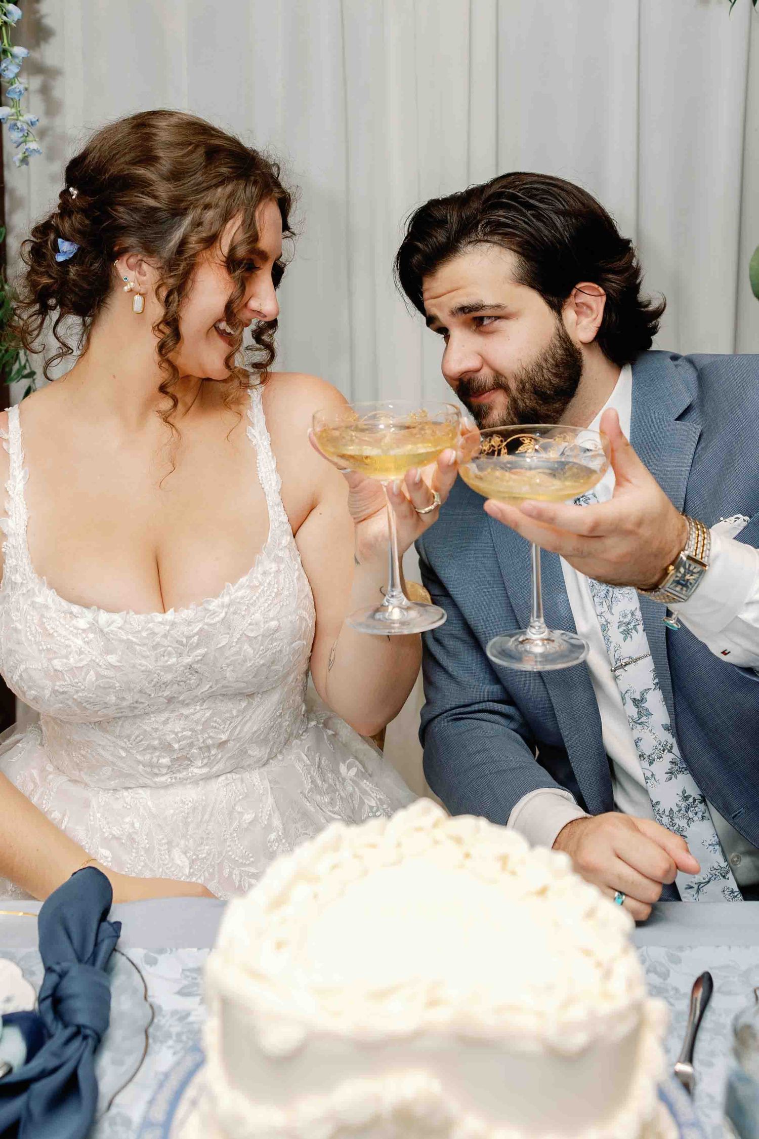 Couple shares cake and champagne at their wedding reception head table.
