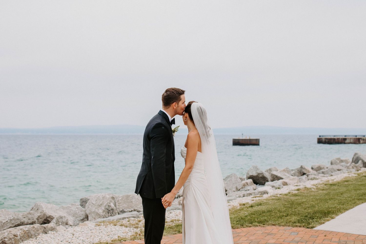 Romantic wedding portraits captured along scenic coastal walkway.