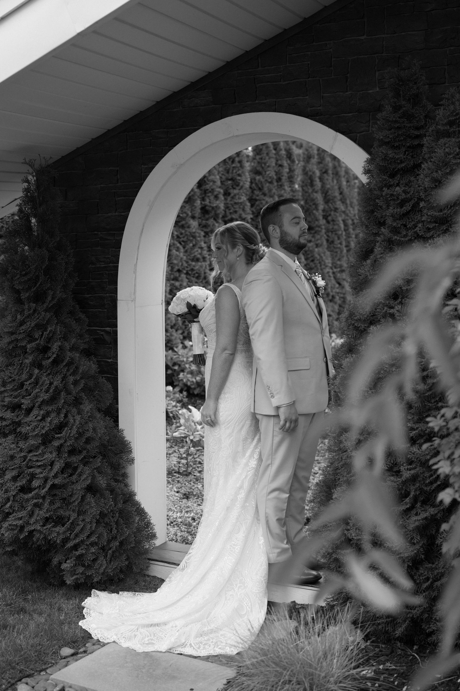 Black and white photo of a couple through an archway on their wedding day.