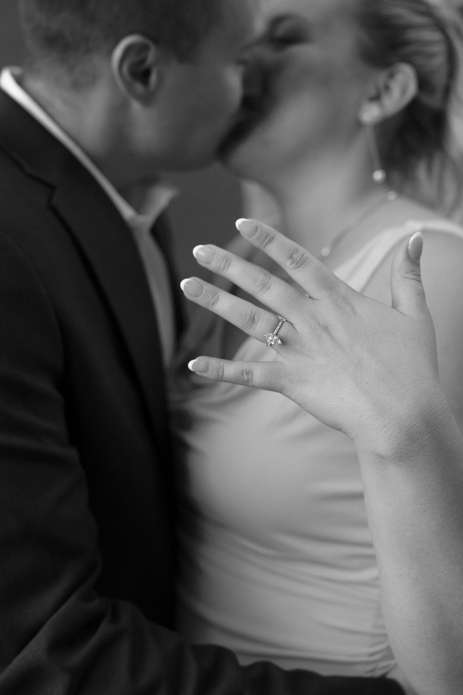 Close-up black and white photo showing hands with engagement ring.